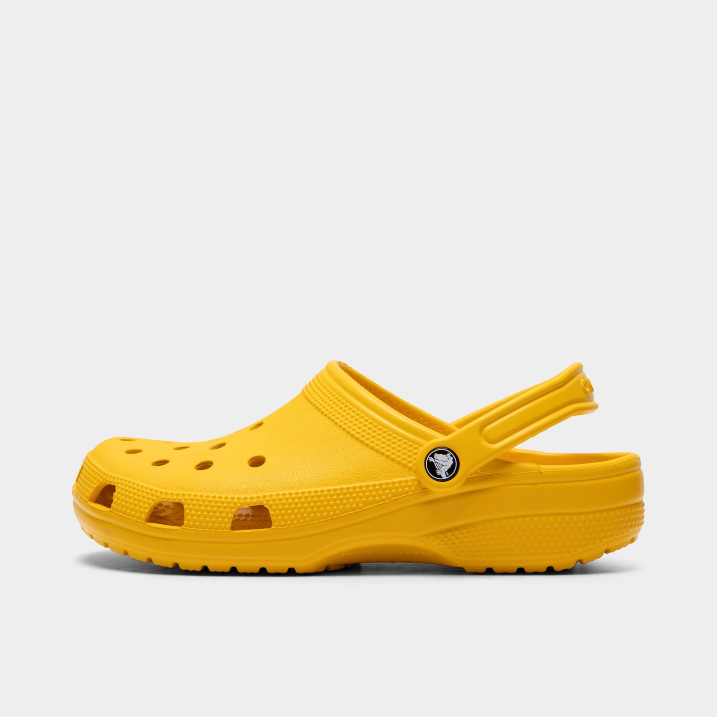 Crocs Classic Clog. Side view of golden light clog with ventilation holes, pivoting heel strap and matching textured sole.