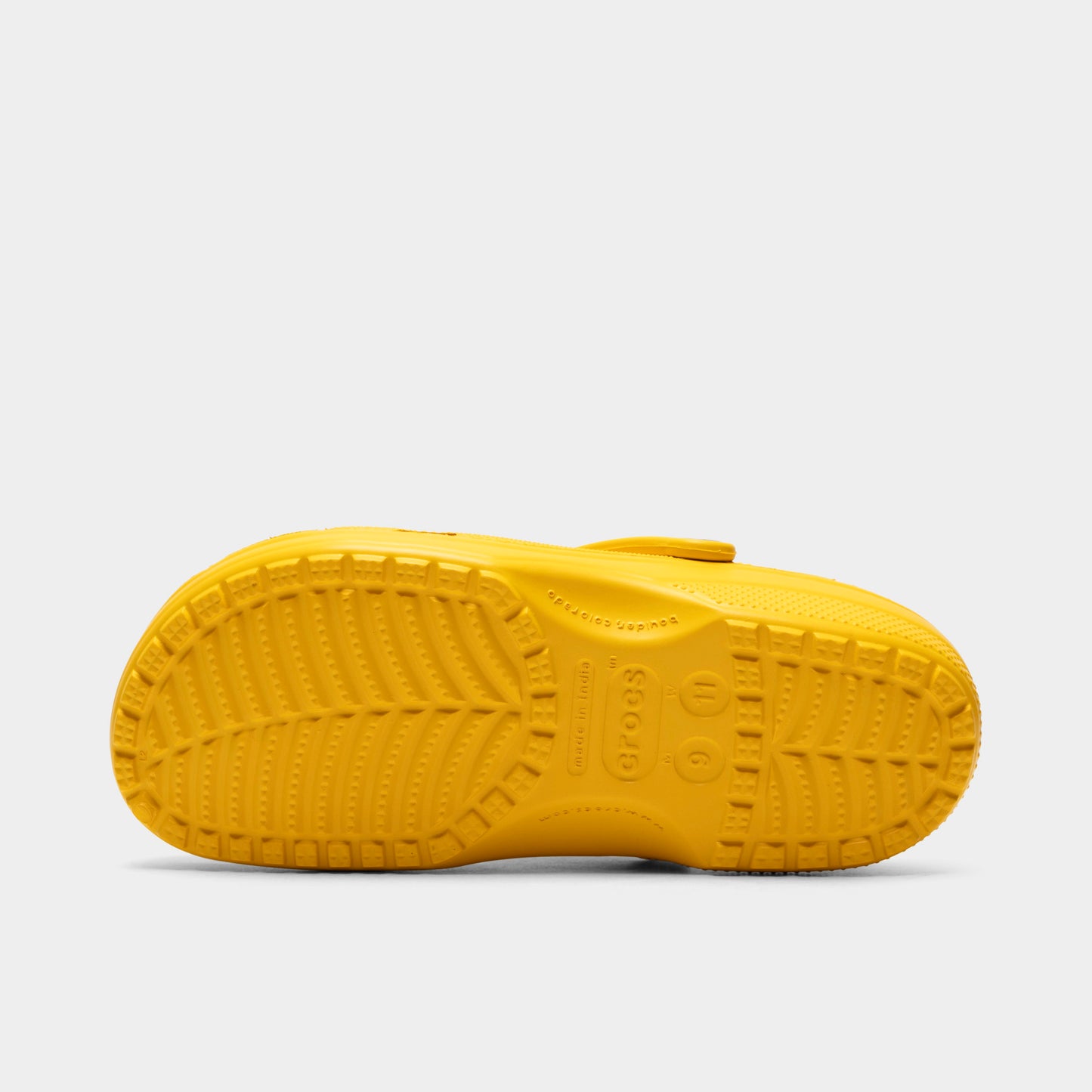 Crocs Classic Clog. Bottom view of golden light clog showing textured outsole with segmented tread pattern.