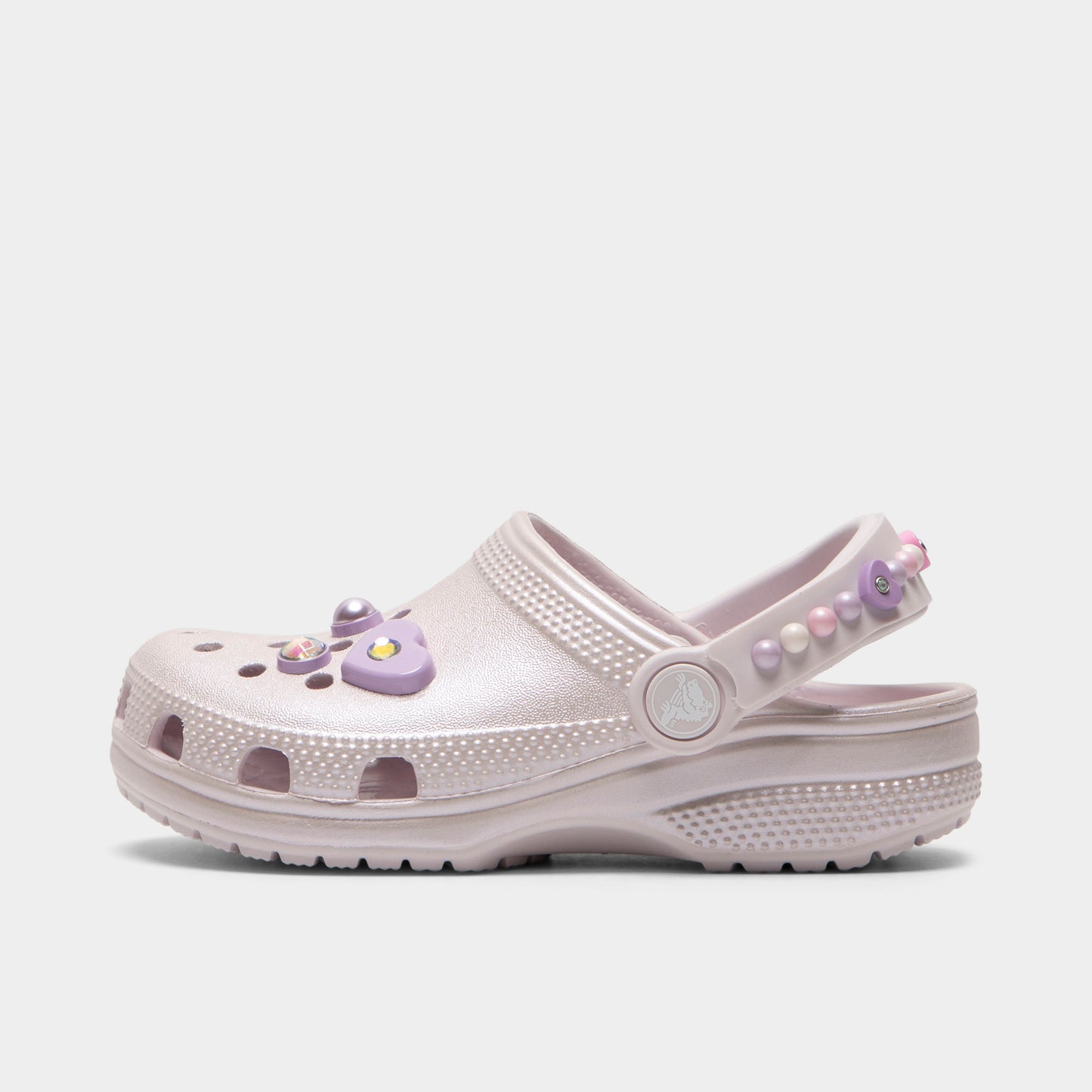Crocs Kids' Classic Pearls and Heart Shine Clog. Side view of grape ice infant clog with ventilation holes, pivoting heel strap and decorative pearl and heart charms.