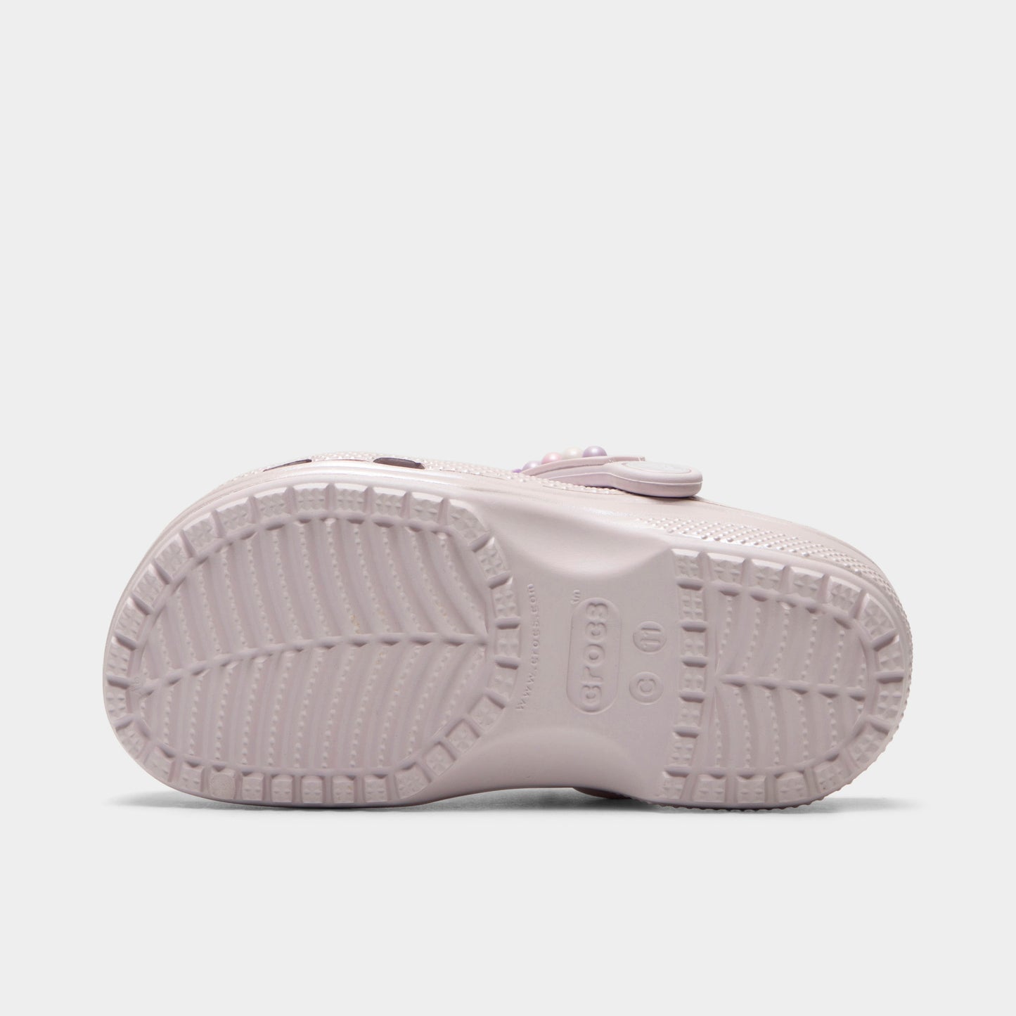 Crocs Kids' Classic Pearls and Heart Shine Clog. Bottom view of grape ice infant clog showing textured outsole with segmented tread pattern.