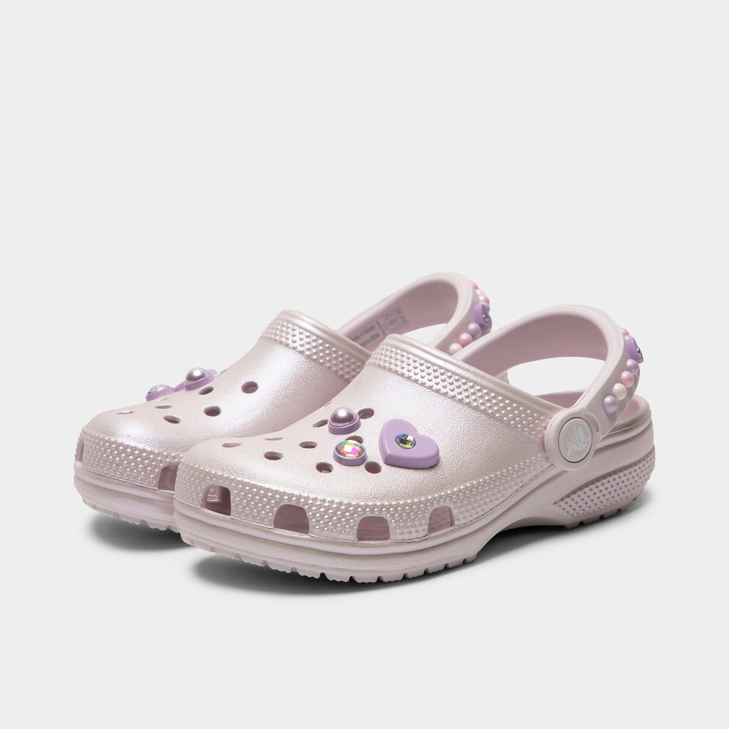 Crocs Kids' Classic Pearls and Heart Shine Clog. Three-quarter view of grape ice infant clogs with ventilation holes, raised heel straps and decorative charms.