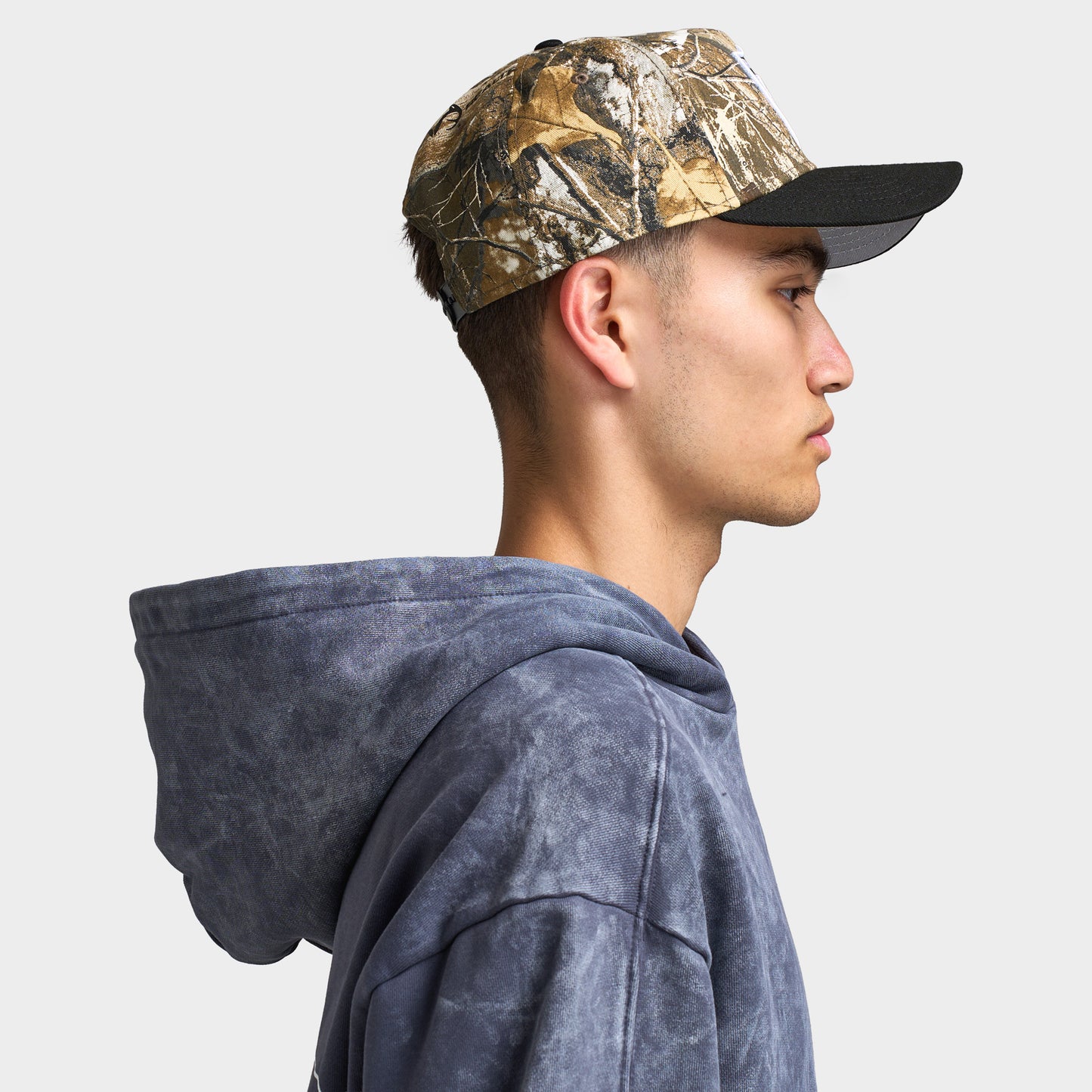 New Era Las Vegas Raiders 9FORTY A-Frame cap. Side profile view of model wearing the Realtree camo and black cap with structured crown and curved black brim.