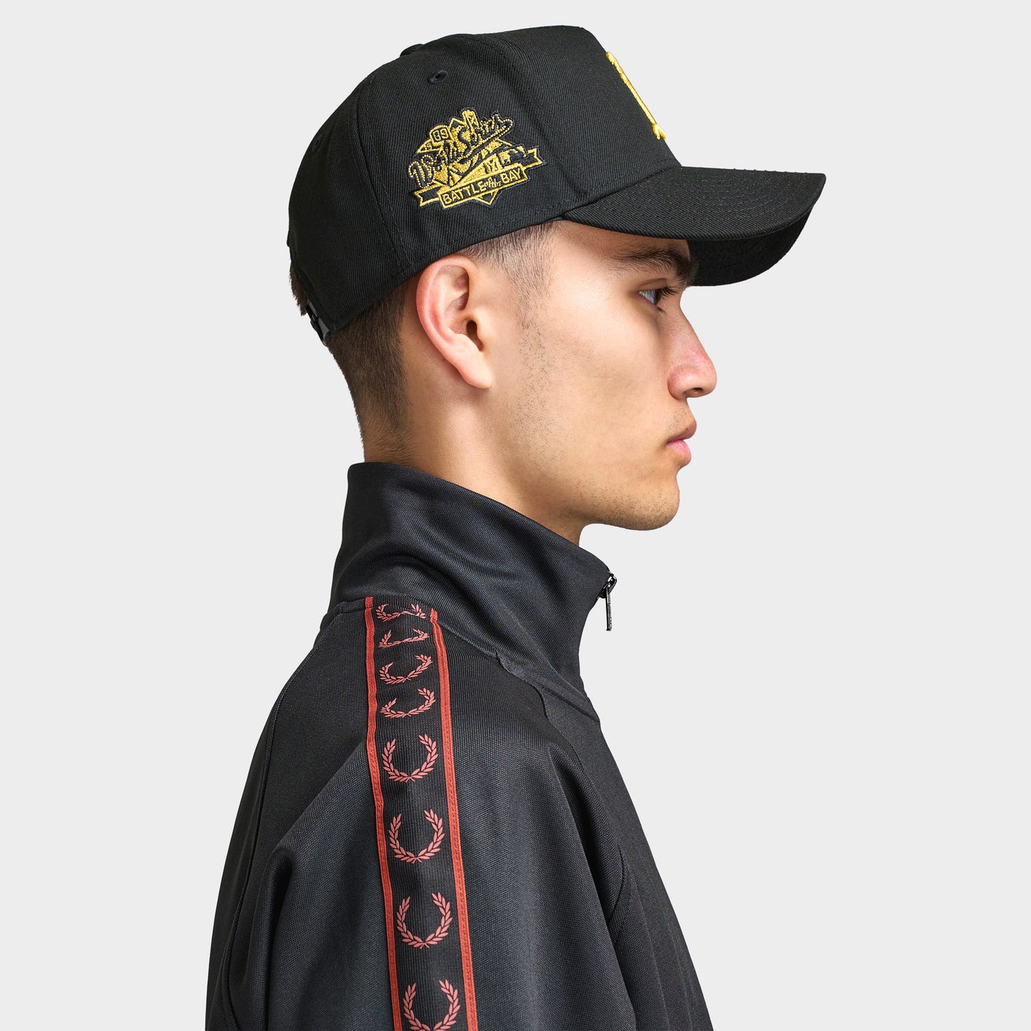New Era Oakland Athletics 9FORTY AF Snapback. Side view of model wearing black cap with curved brim, gold side embroidery and structured profile.