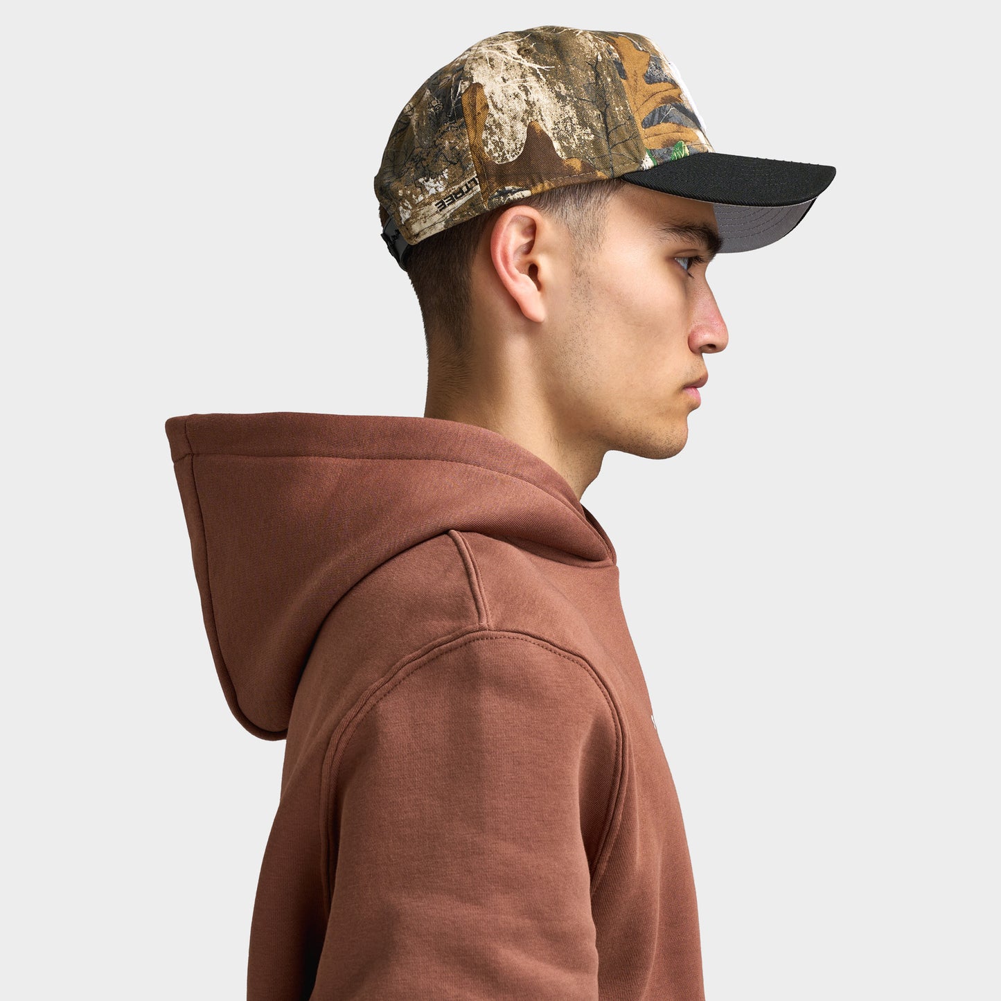 New Era Detroit Tigers 9FORTY AF. Side view of model wearing real tree camo and black cap with curved brim, camouflage crown and structured profile.