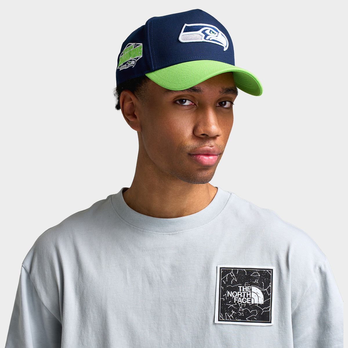 Era Seattle Seahawks 9FORTY A-Frame. Front view on model featuring a navy crown, embroidered Seahawks logo, vibrant action green visor, and side patch.