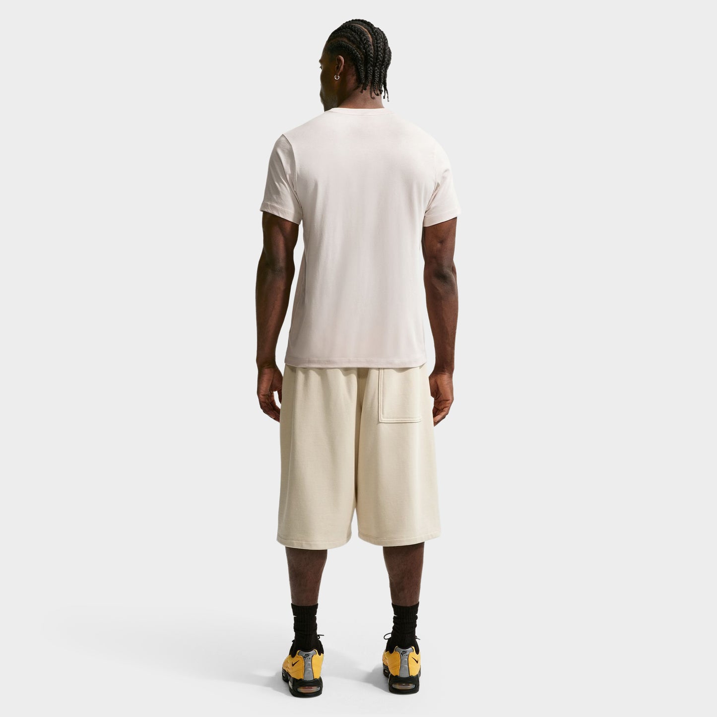 Nike Sportswear Club Tee. Full-body back view of model wearing light orewood brown T-shirt with matching shorts and dark shoes.