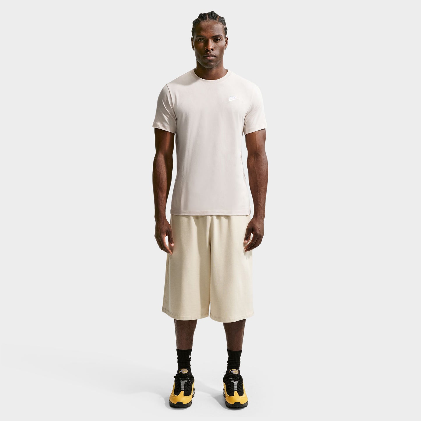 Nike Sportswear Club Tee. Full-body front view of model wearing light orewood brown T-shirt with matching shorts and dark shoes.