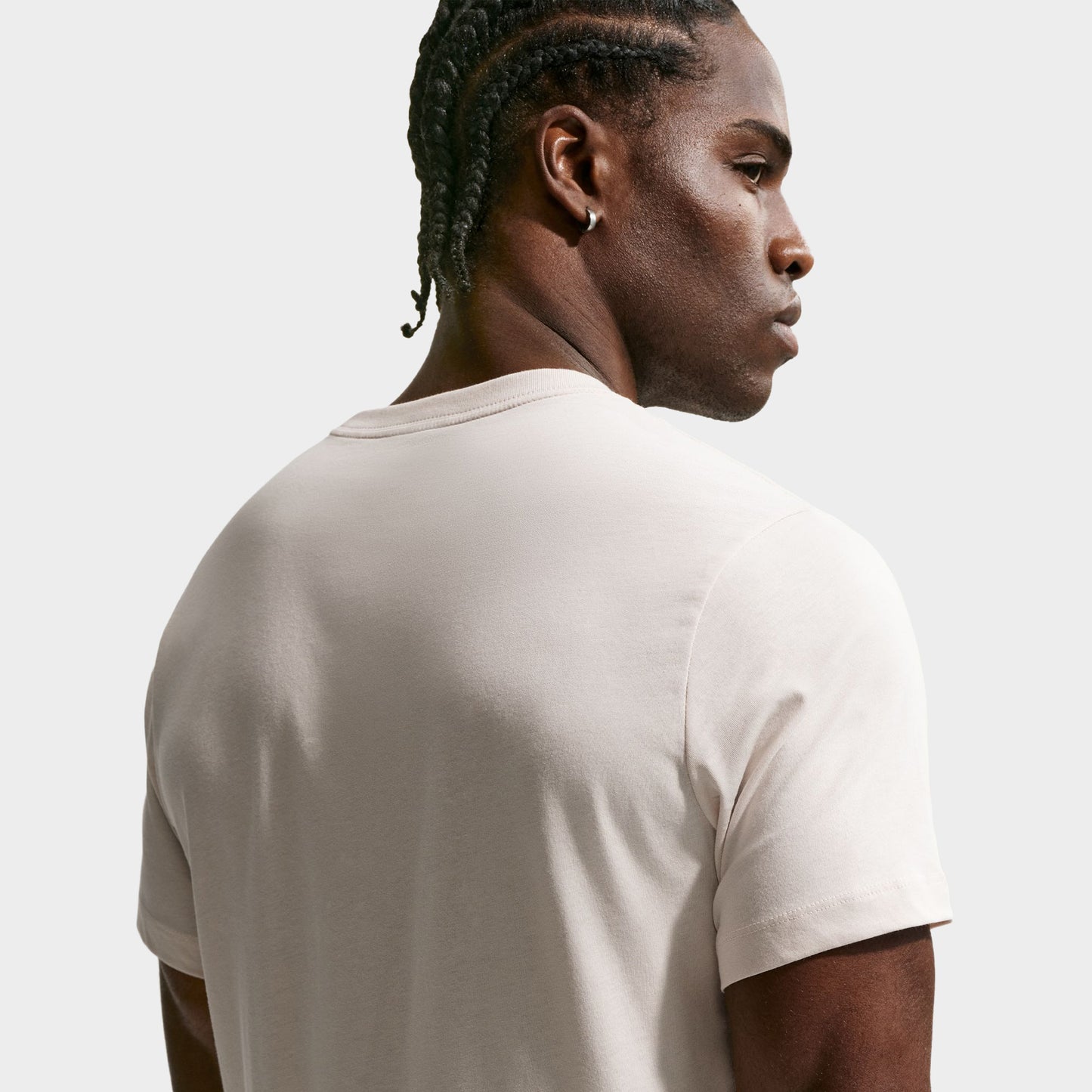 Nike Sportswear Club Tee. Back three-quarter view of model wearing light orewood brown T-shirt with plain back and relaxed fit.