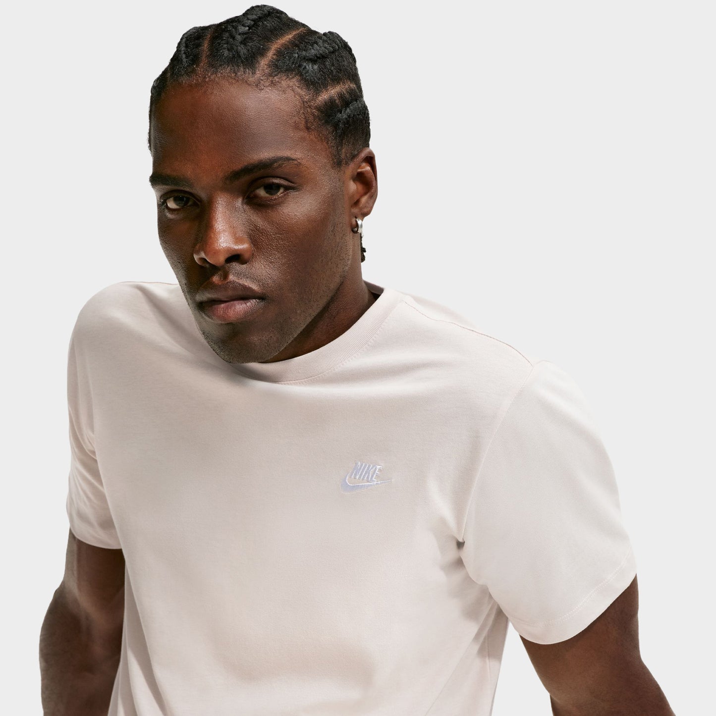Nike Sportswear Club Tee. Three-quarter view of model wearing light orewood brown T-shirt with crew neckline, short sleeves and small white Nike Swoosh.