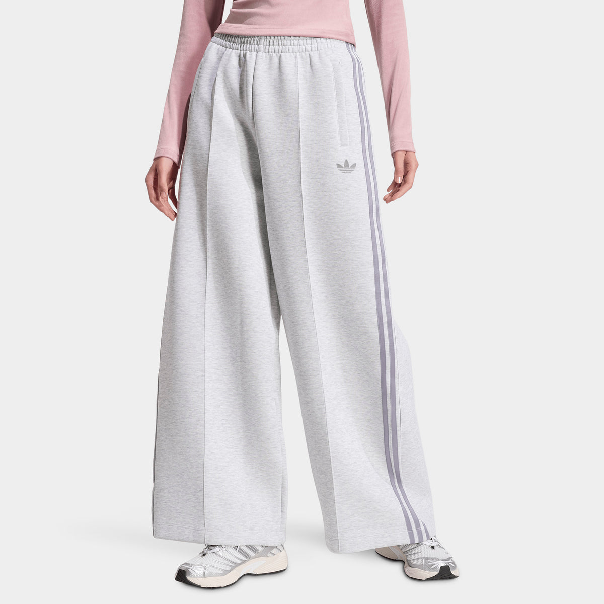 adidas Spacer Track Pants. Front view of model wearing light grey heather and silver track pants with wide legs, elastic waistband and tonal Trefoil logo.