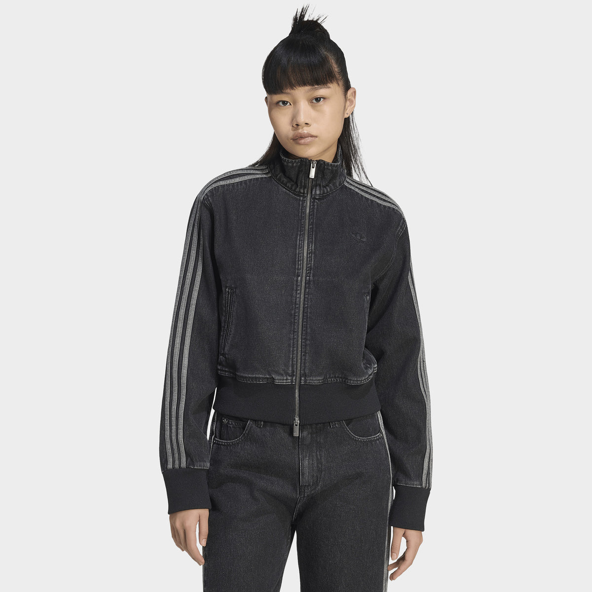 adidas Firebird Denim Track Top. Front view of model wearing true black denim track jacket with full-zip closure, high collar and tonal three stripes.