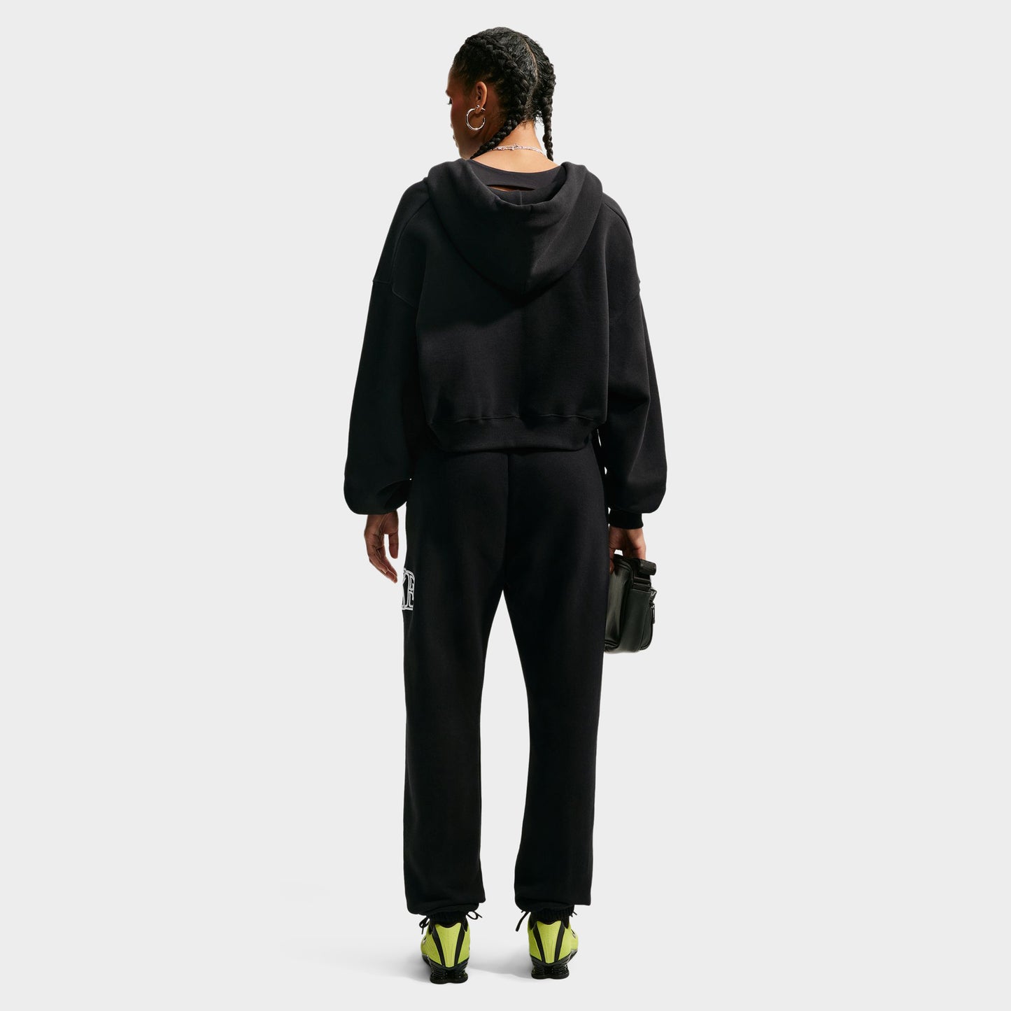 Nike Studio Fleece Cropped Full Zip Hoodie. Full-body back view of model wearing black cropped hoodie with matching black pants.