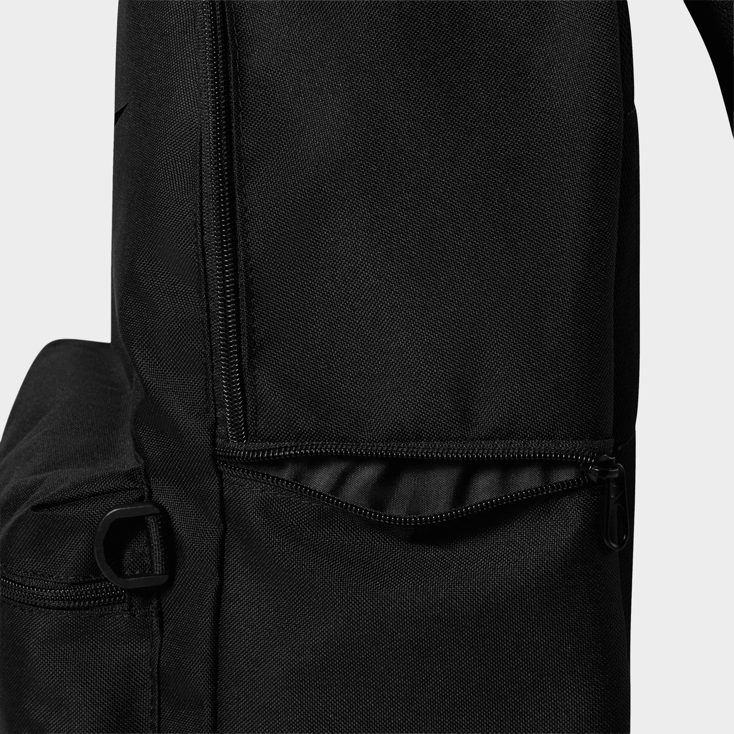 Nike AF1 Heritage Backpack. Close-up of black backpack showing side pocket, adjustable strap and stitched panel details.