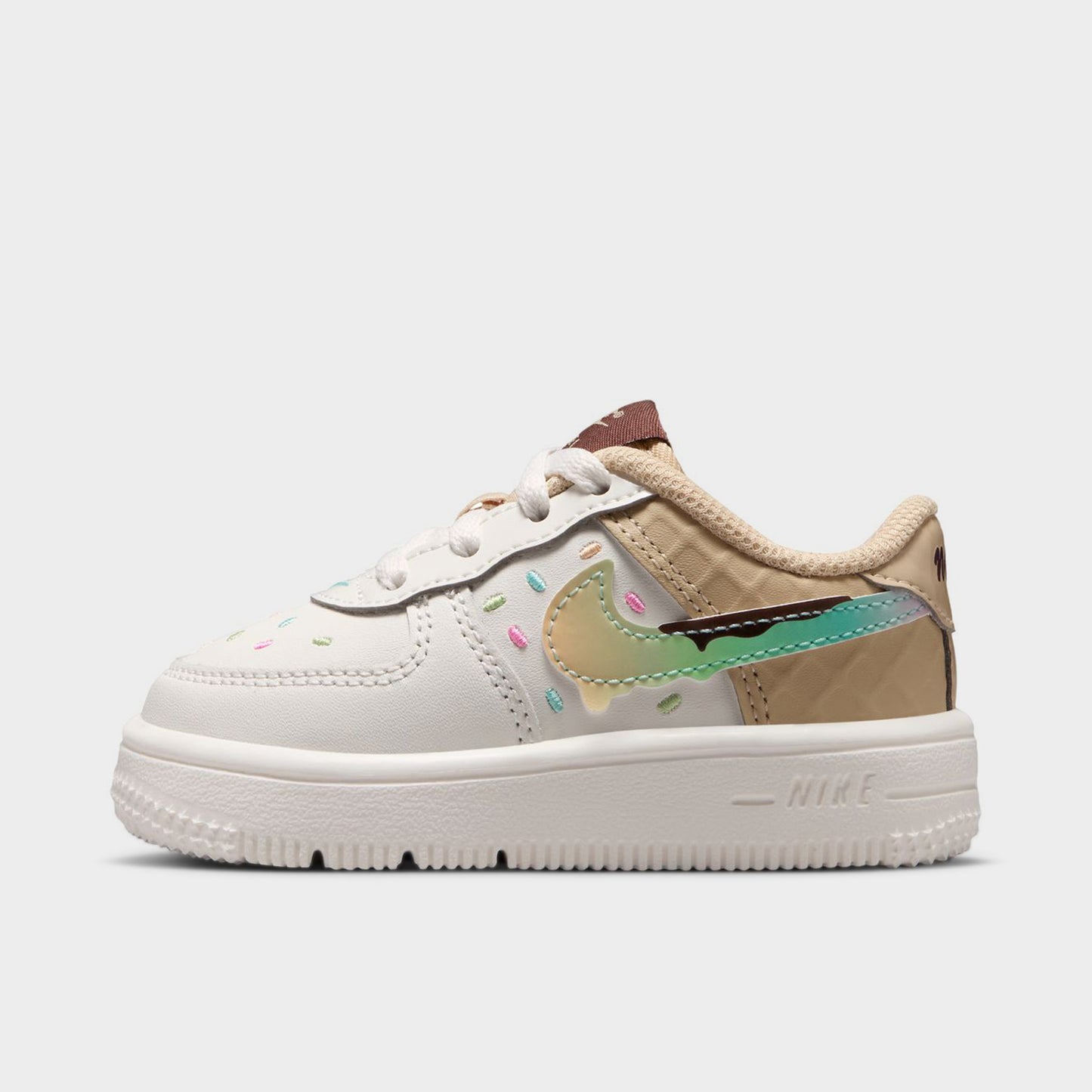 Nike Air Force 1 TD. Side view of sail, multicolour and sesame toddler sneaker with pastel Swoosh, stitched overlays, beige collar and white sole.