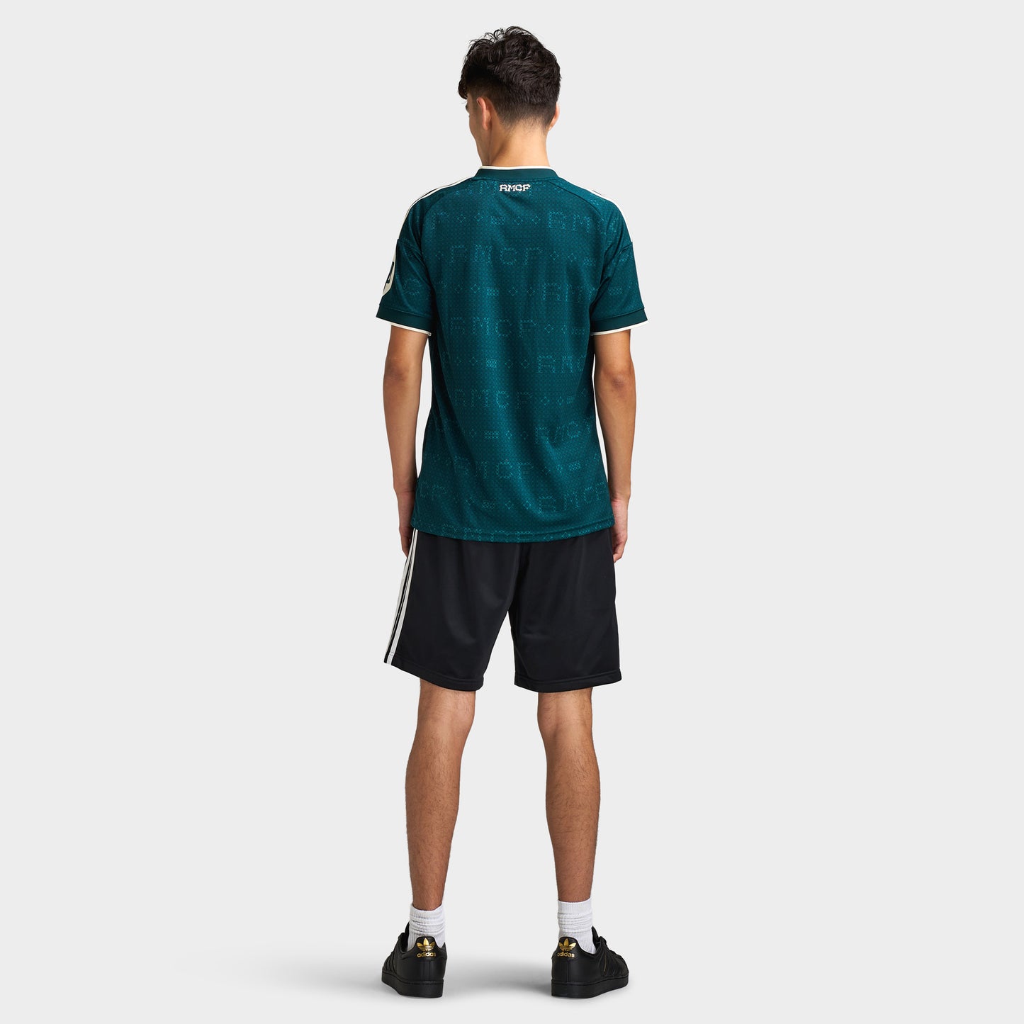 adidas Real Madrid Away Jersey. Full-body back view of model wearing aurora ivy soccer jersey with black shorts and dark shoes.