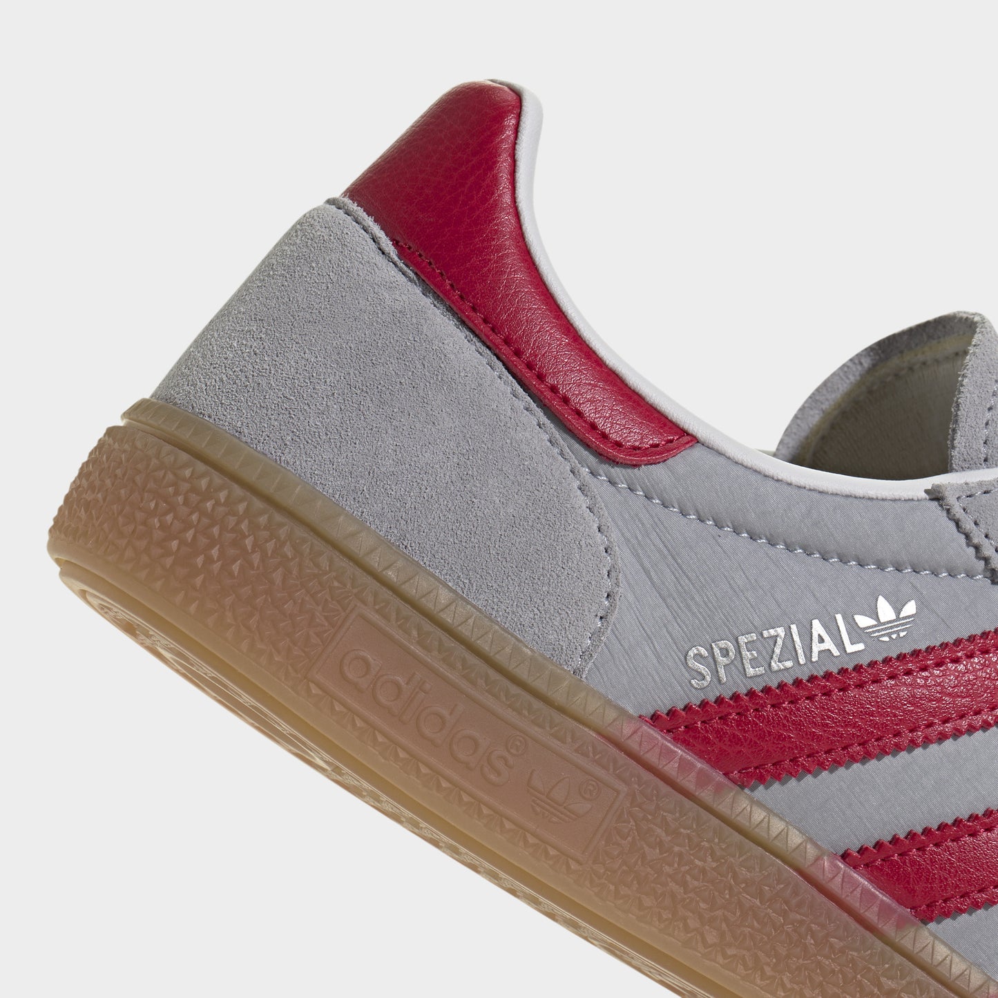 adidas Handball Spezial. Close-up of halo silver, team victory red and gum sneaker showing red heel tab, padded collar and textured gum sole edge.