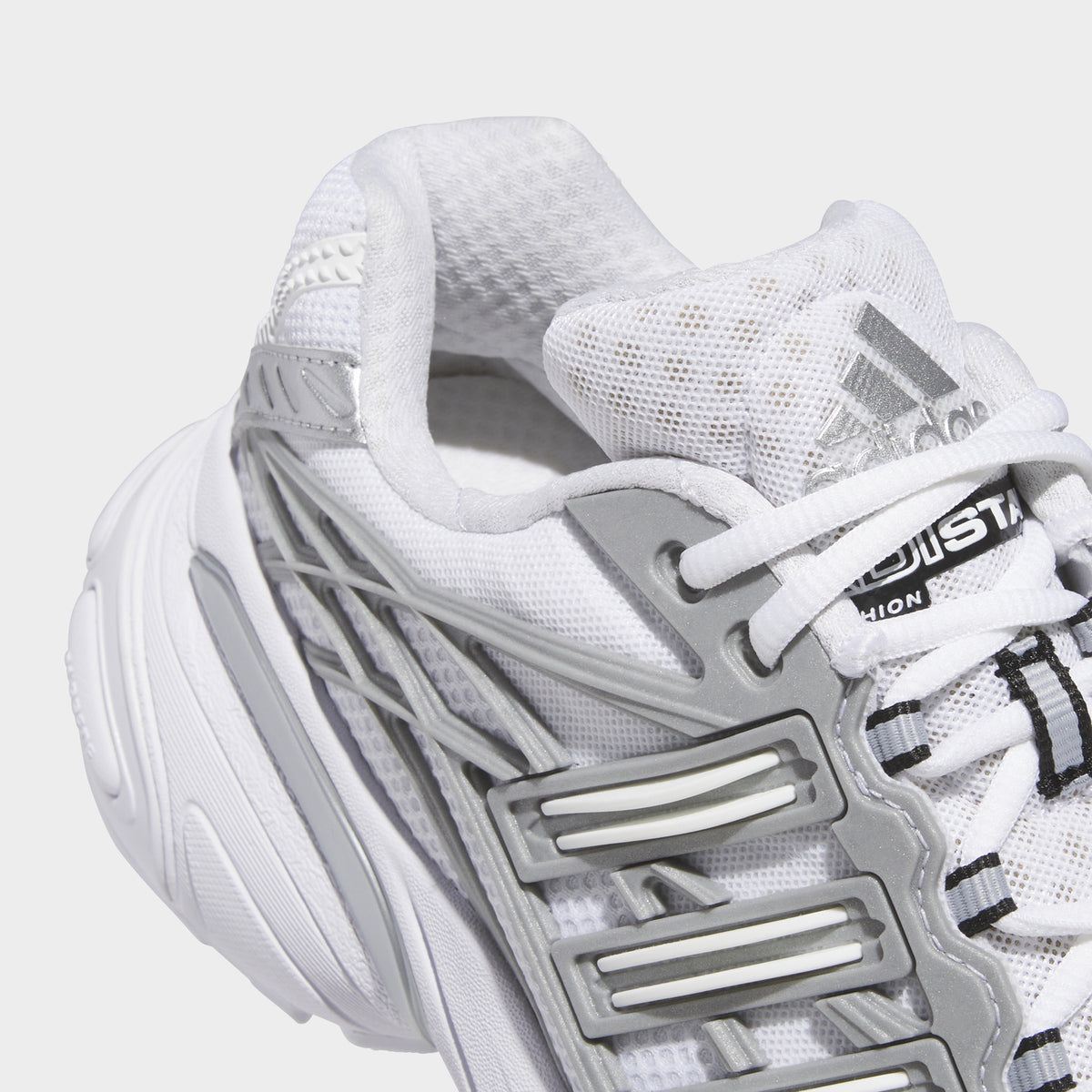 adidas Adistar XLG 2.0. Close-up of footwear white and silver metallic sneaker showing white laces, mesh panels and three stripes.