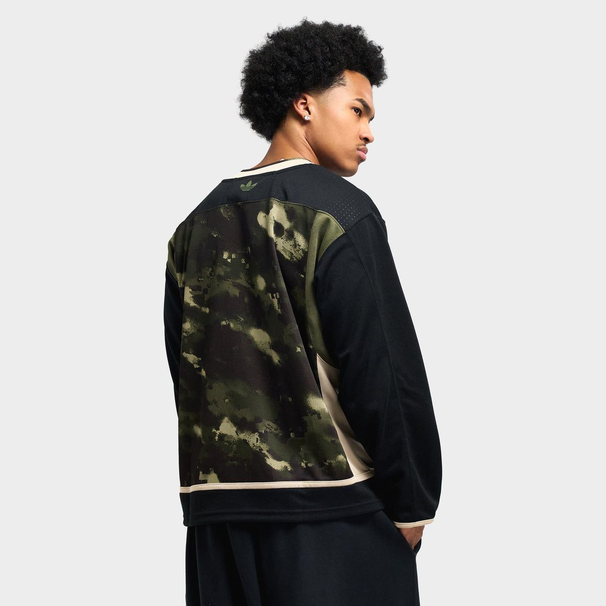 adidas Hockey Jersey. Three-quarter back view displaying black mesh sleeves, olive strata camo body, cream hem trim, and relaxed sports fit.