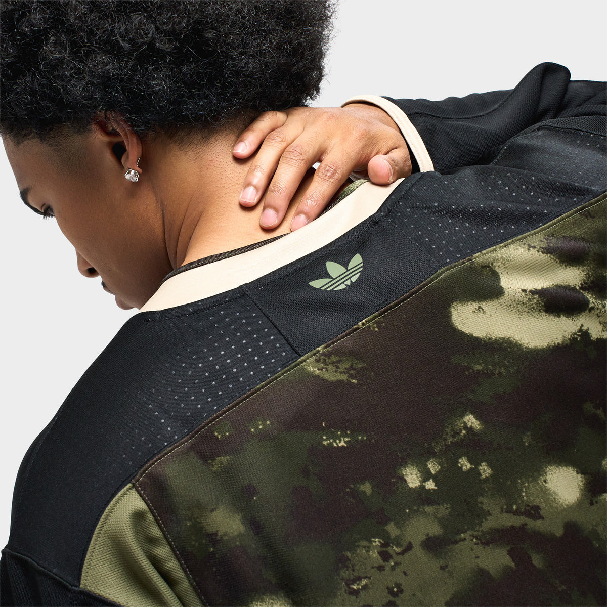 adidas Hockey Jersey. Close-up rear neck view showcasing black mesh shoulder panel, cream rib collar, and green embroidered adidas Trefoil logo at the upper back.