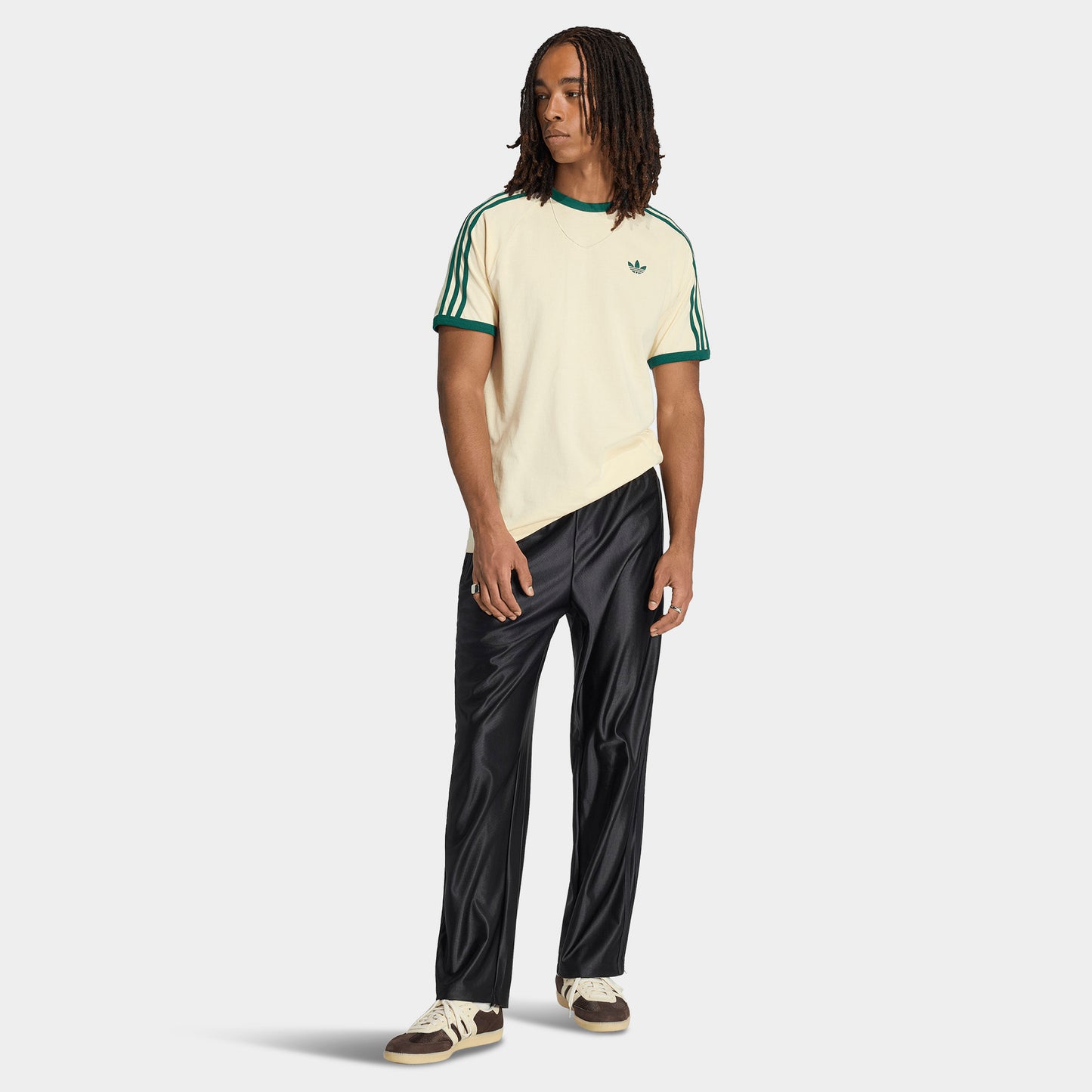 adidas 3 Stripes T-Shirt. Full-body view of model wearing vanilla and collegiate green T-shirt with black pants and light-coloured shoes.