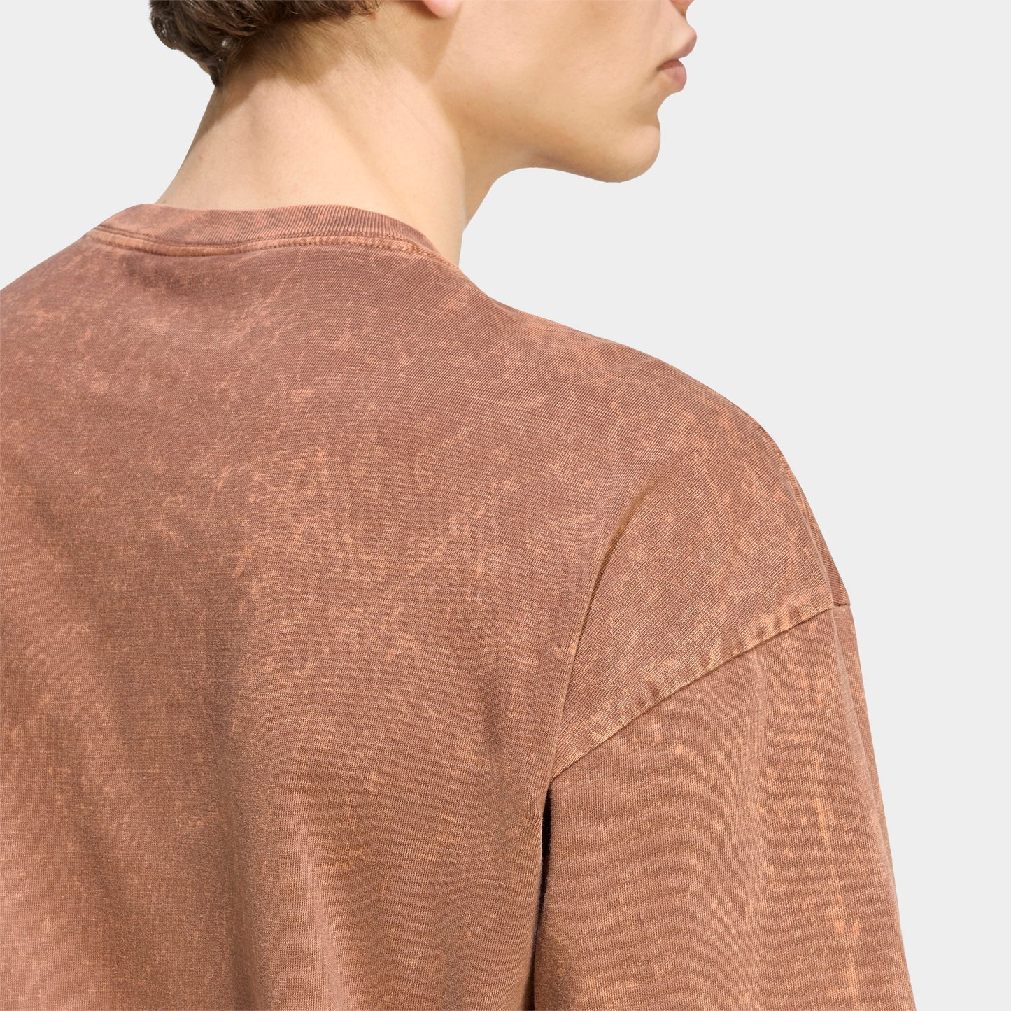 adidas Trefoil Essential Washed Loose T-Shirt. Close-up of preloved brown T-shirt showing washed texture, crew neckline and relaxed shoulder seams.
