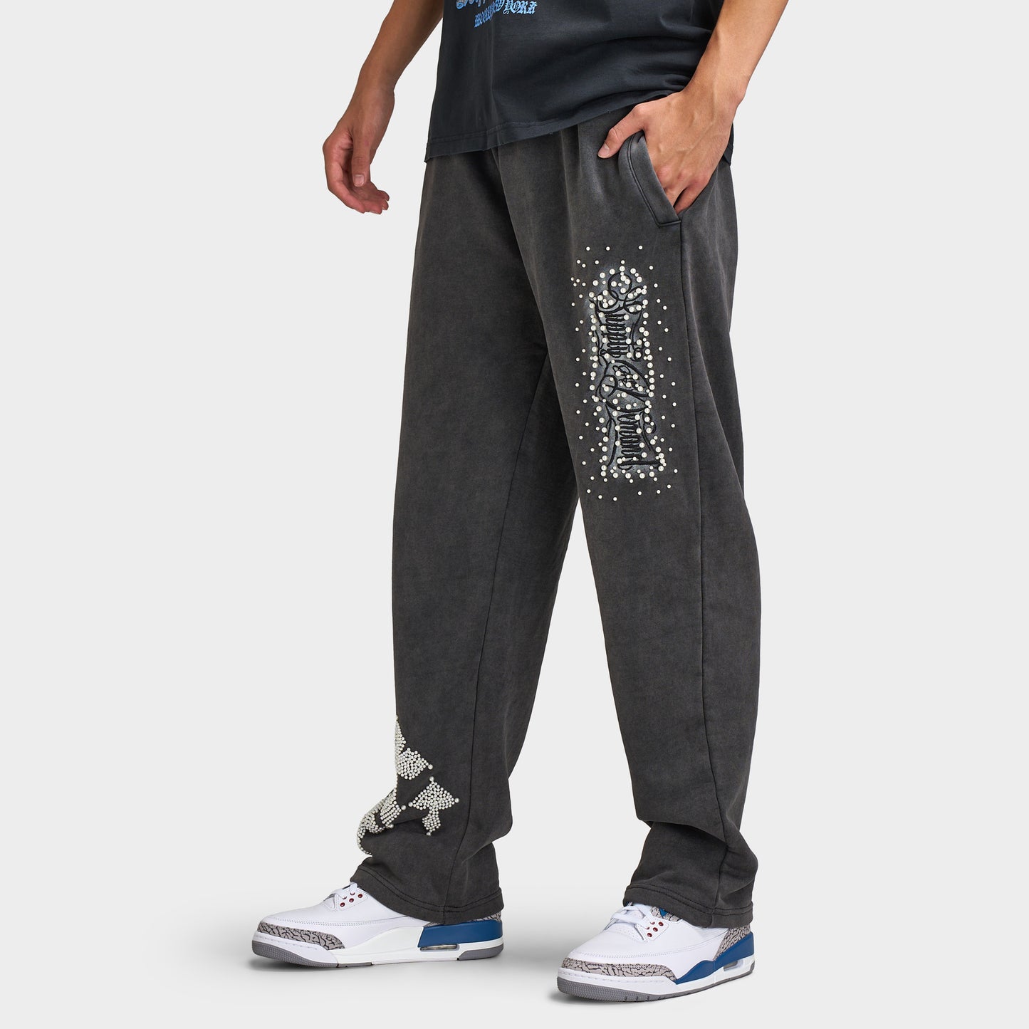 Supply & Demand Murphy Oversized Pants. Side view of model wearing black oversized pants with relaxed legs, side pocket and white graphic print.