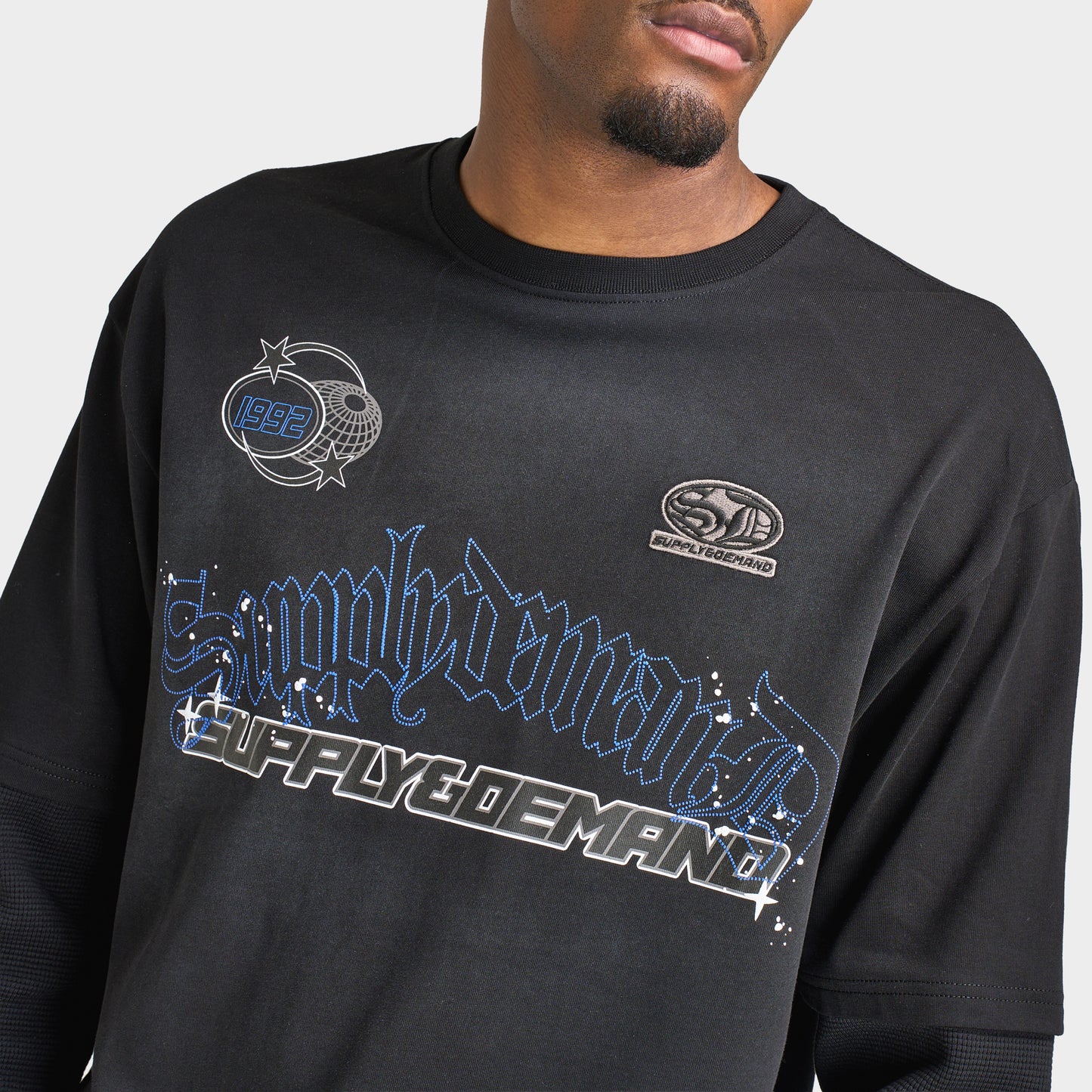Supply & Demand Global Longsleeve Tee. Close-up of black long-sleeve T-shirt showing large blue and grey Supply & Demand graphic across the chest.