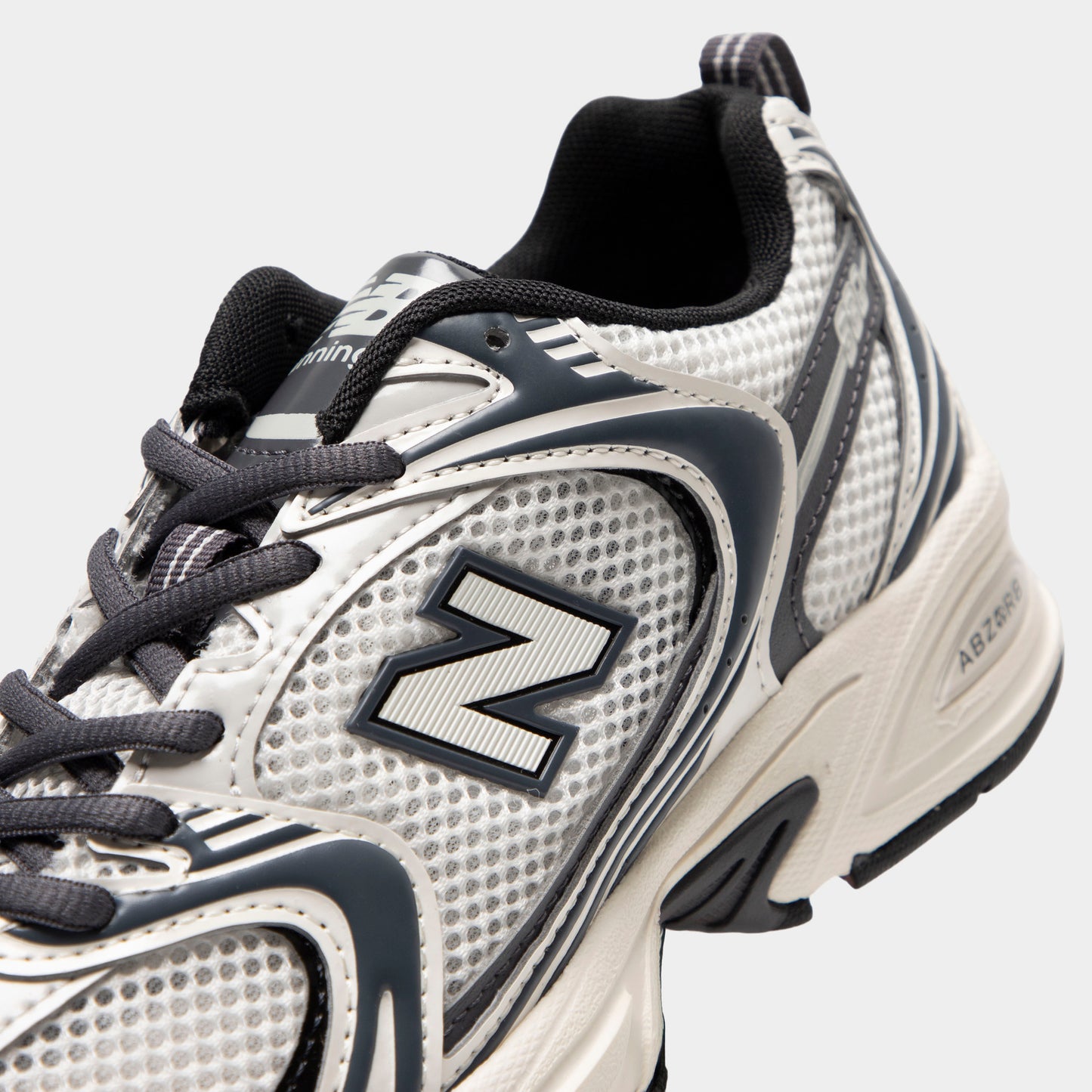 New Balance 530. Close-up of sea salt and magnet sneaker showing grey laces, mesh panels, layered overlays and N logo.