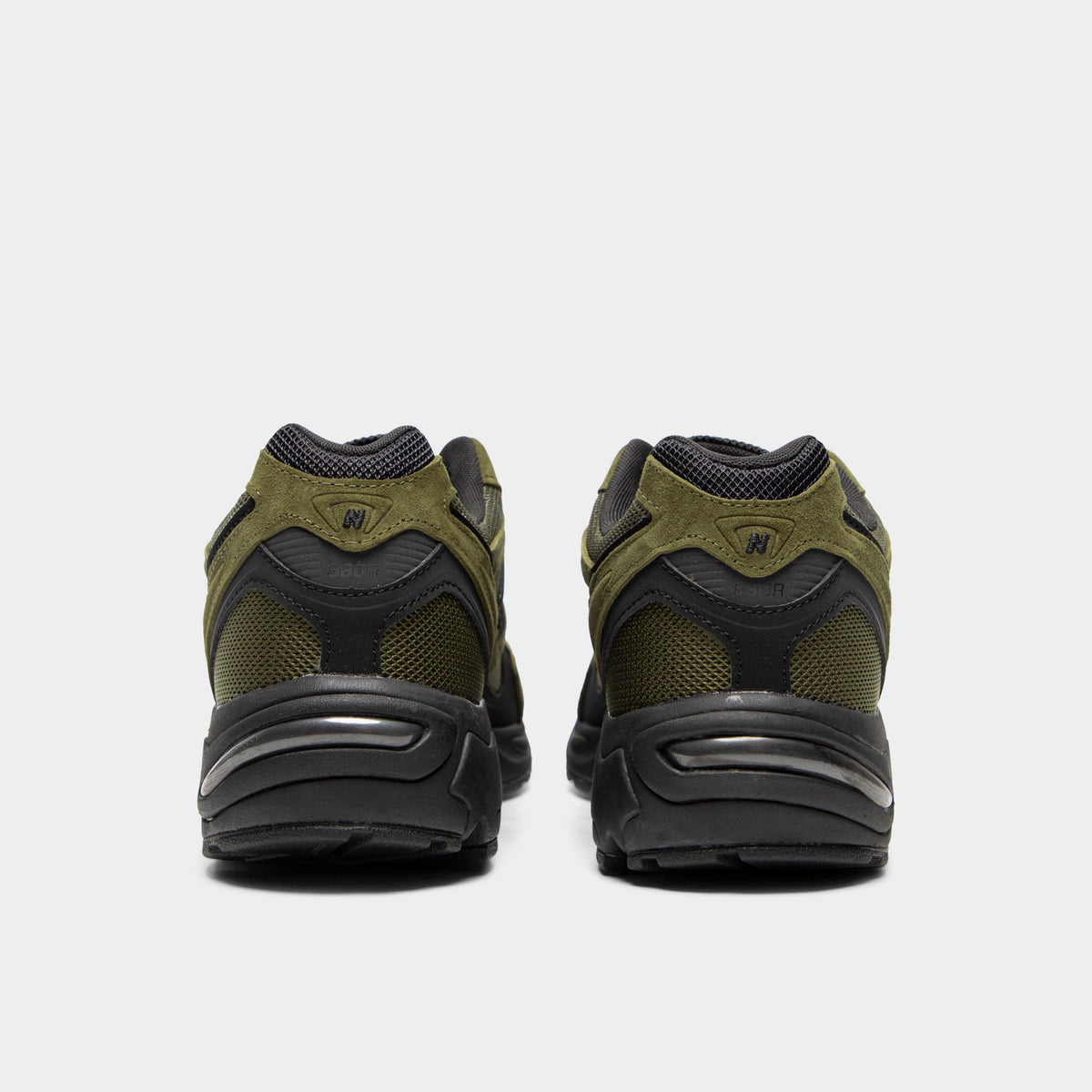 New Balance 880. Rear view of a pair of low-top sneakers displaying wakame olive green mesh and suede heel counters, black leather rear overlays, black padded collar linings, and black midsoles.