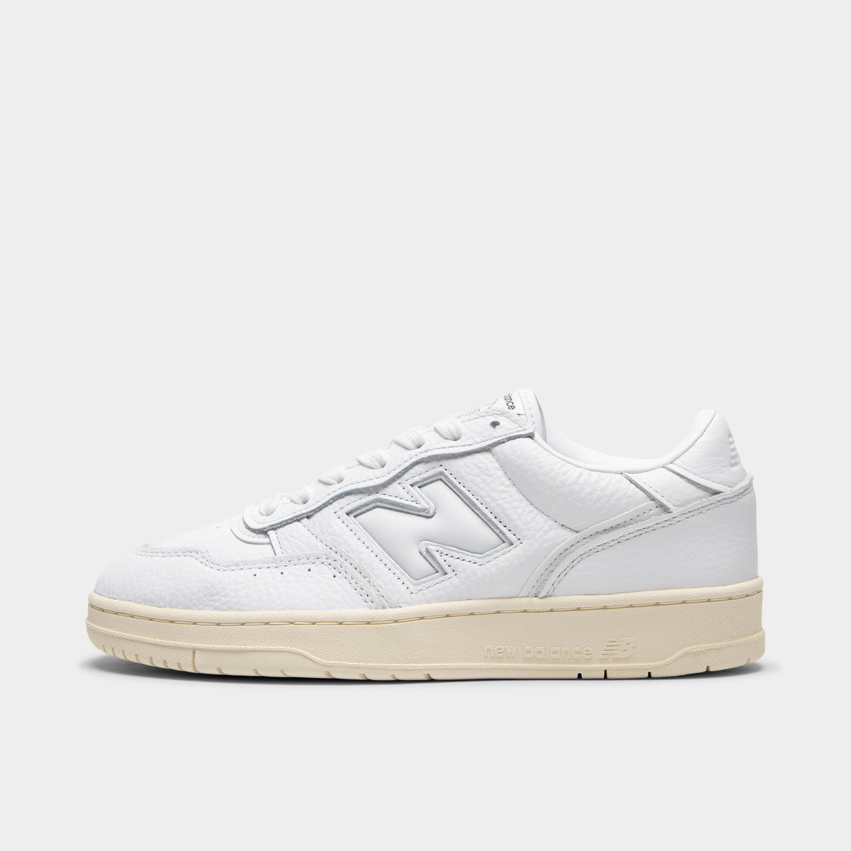 New Balance 950. Side view of low-top sneakers featuring a white leather upper, white padded leather "N" logo on the midfoot with tonal stitching, white laces, white padded collar, off-white aged rubber cupsole, and an off-white rubber outsole.