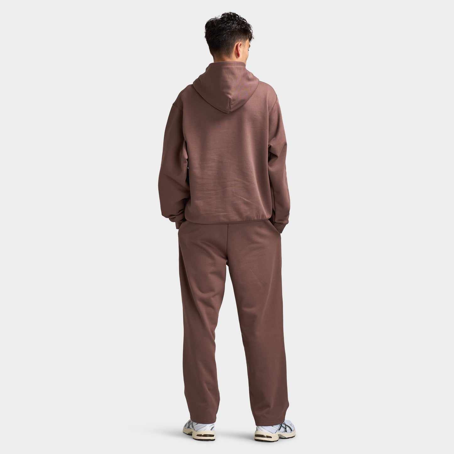 Unlike Humans Ridge Hoodie. Full-body back view of model wearing coffee quarts hoodie with raised hood and matching pants.