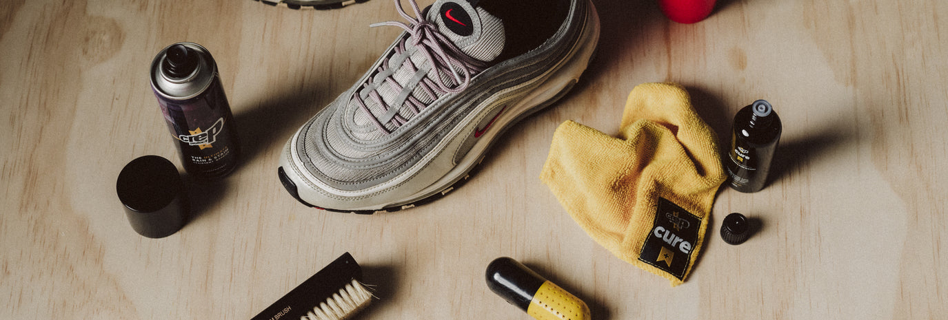 A man is cleaning his sneakers with Crep Protect spray