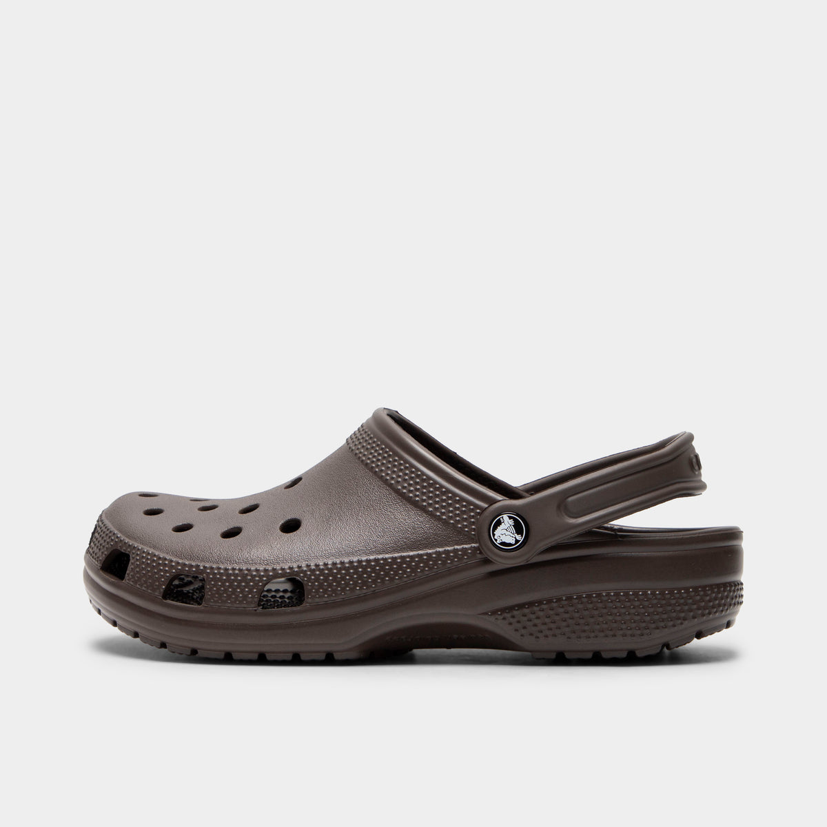 Crocs Classic Clog. Side view of espresso clog with ventilation holes, pivoting heel strap and matching textured sole.