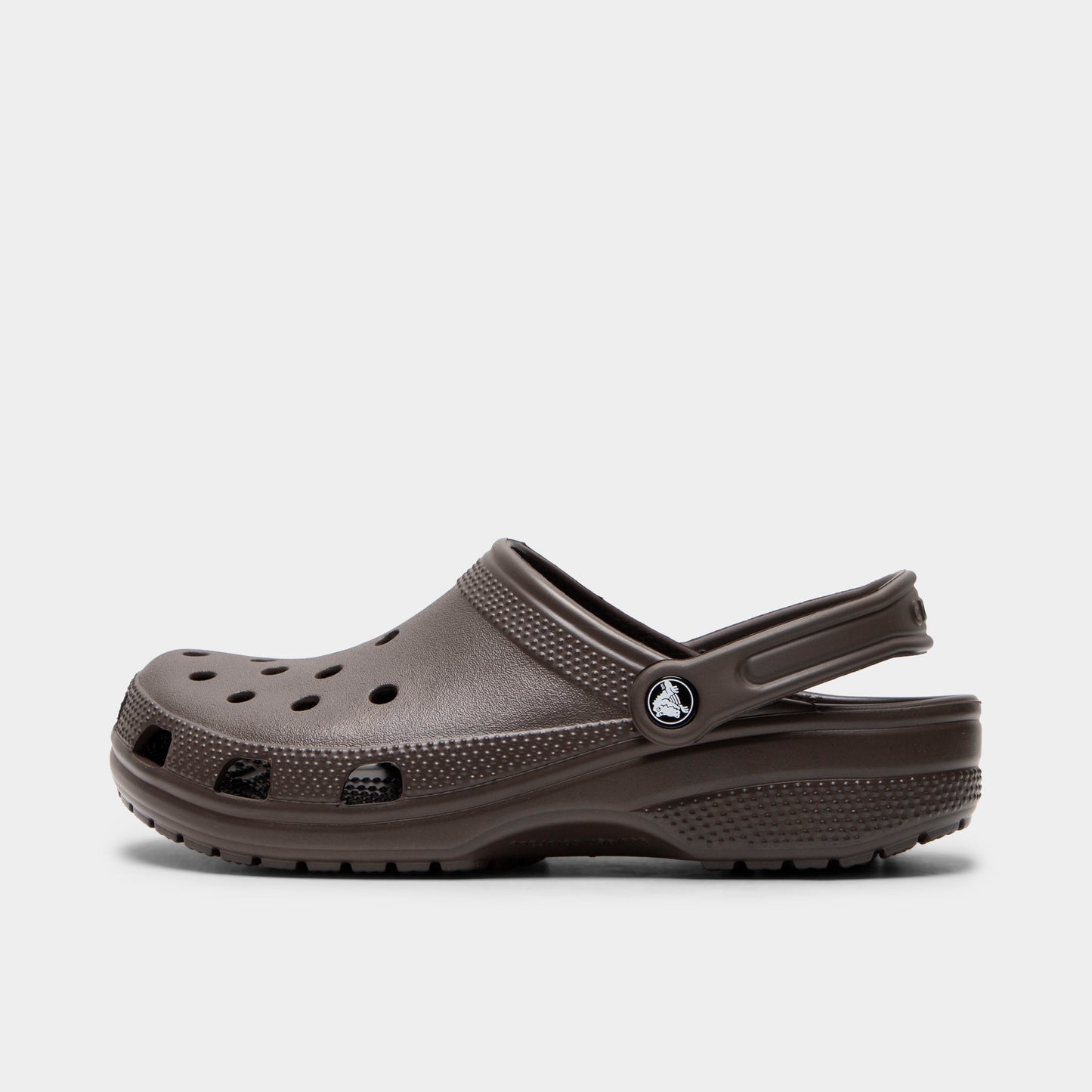 Crocs Classic Clog. Side view of espresso clog with ventilation holes, pivoting heel strap and matching textured sole.