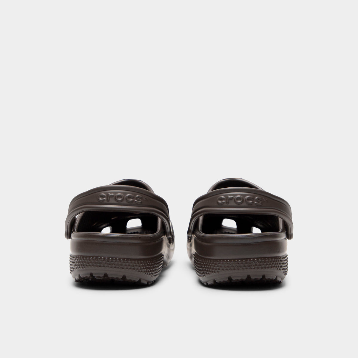 Crocs Classic Clog. Rear view of espresso clogs with lowered heel straps, rounded heels and matching soles.