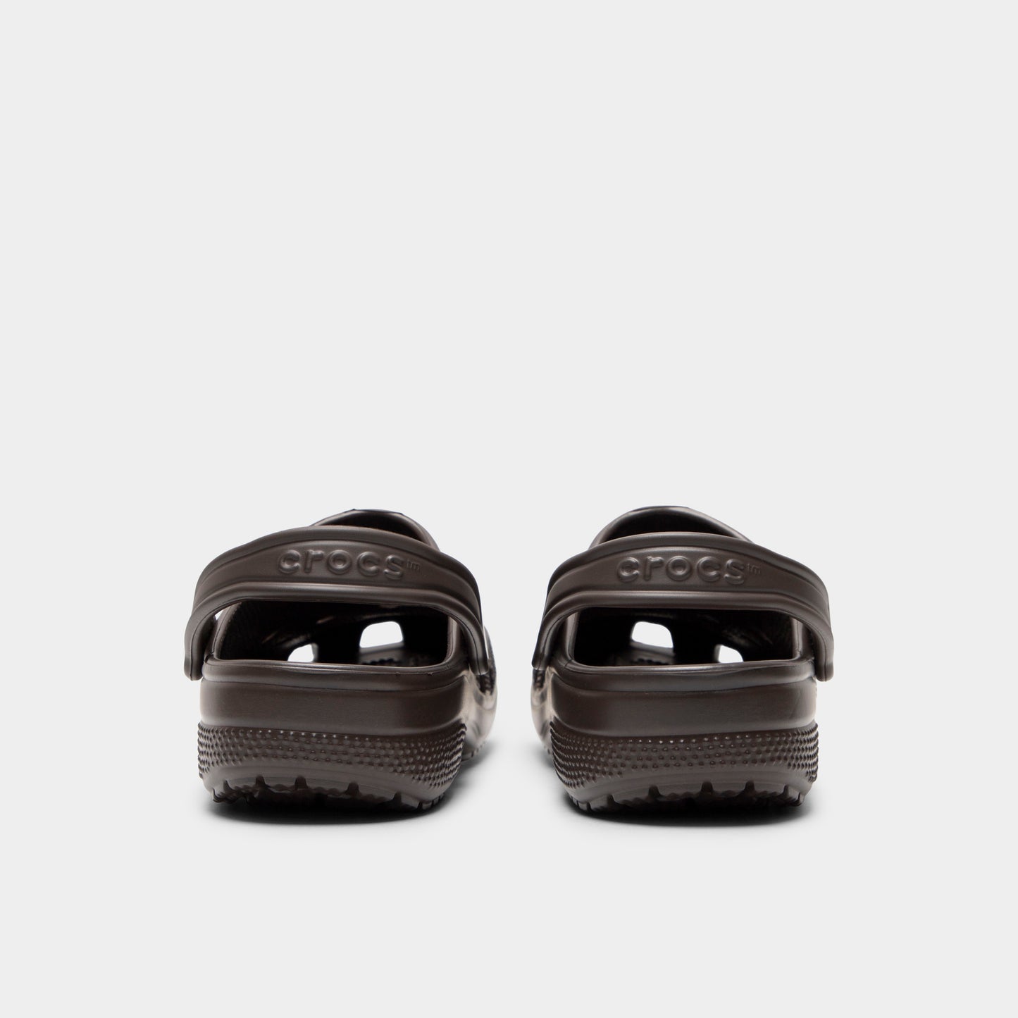 Crocs Classic Clog. Rear view of espresso clogs with lowered heel straps, rounded heels and matching soles.