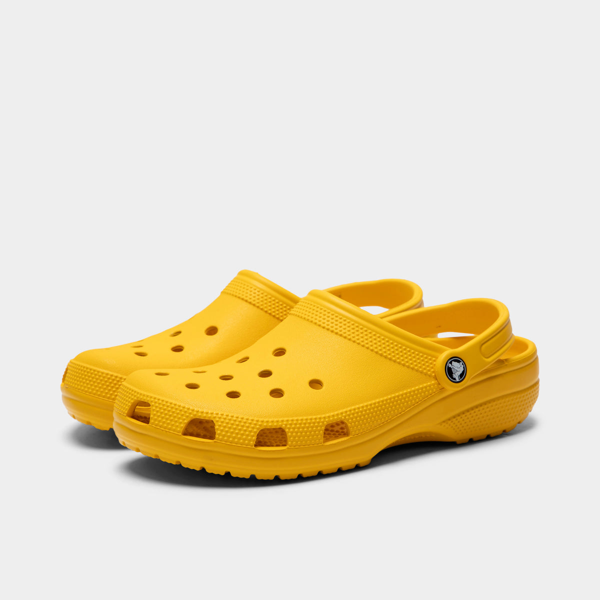 Crocs Classic Clog. Three-quarter view of golden light clogs with ventilation holes, raised heel straps and rounded toes.
