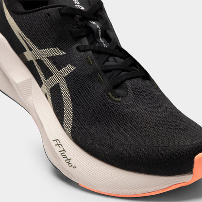 ASICS Novablast 6. Close-up of black and khaki running shoe showing black laces, mesh upper, khaki ASICS stripes and sculpted midsole.