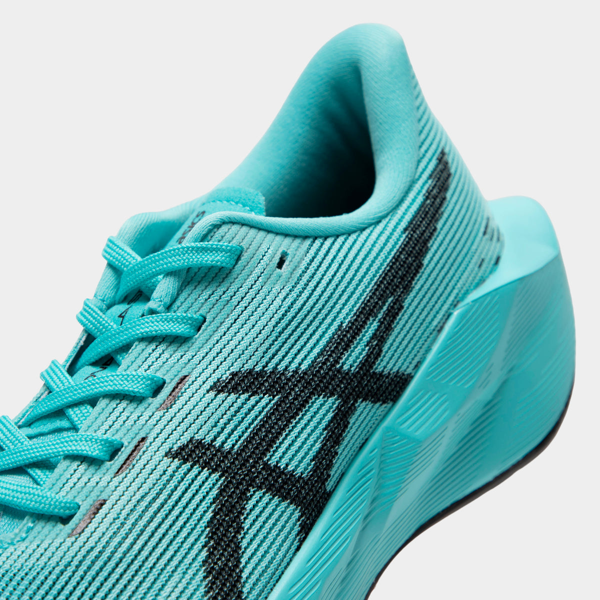 ASICS Juniors' Novablast 5. Close-up of ice mint and black junior running shoe showing tonal laces, mesh panels, black ASICS stripes and padded collar.