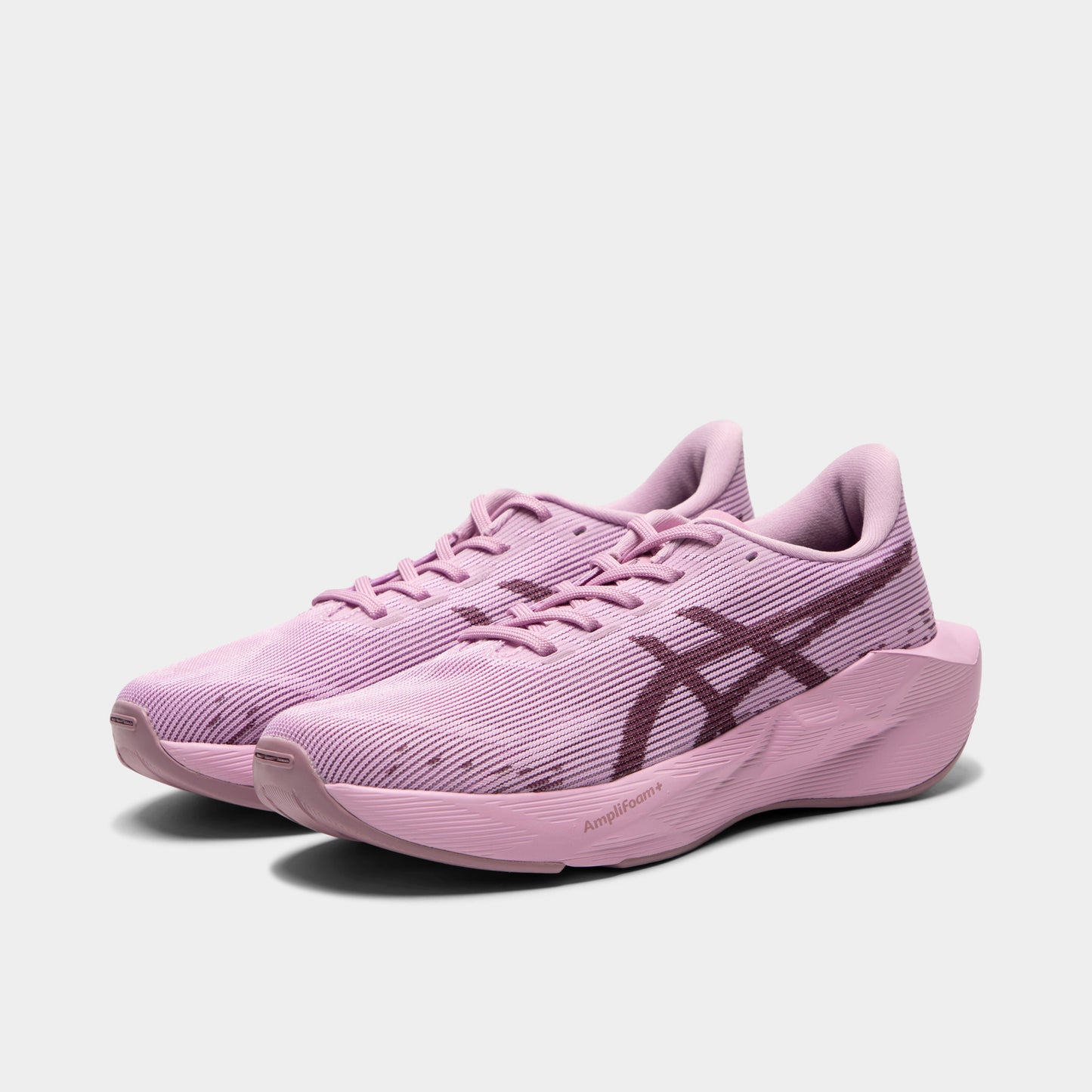 ASICS Juniors' Novablast 5. Three-quarter view of hazy lilac and dark prune junior running shoes with tonal laces, dark ASICS branding and cushioned soles.