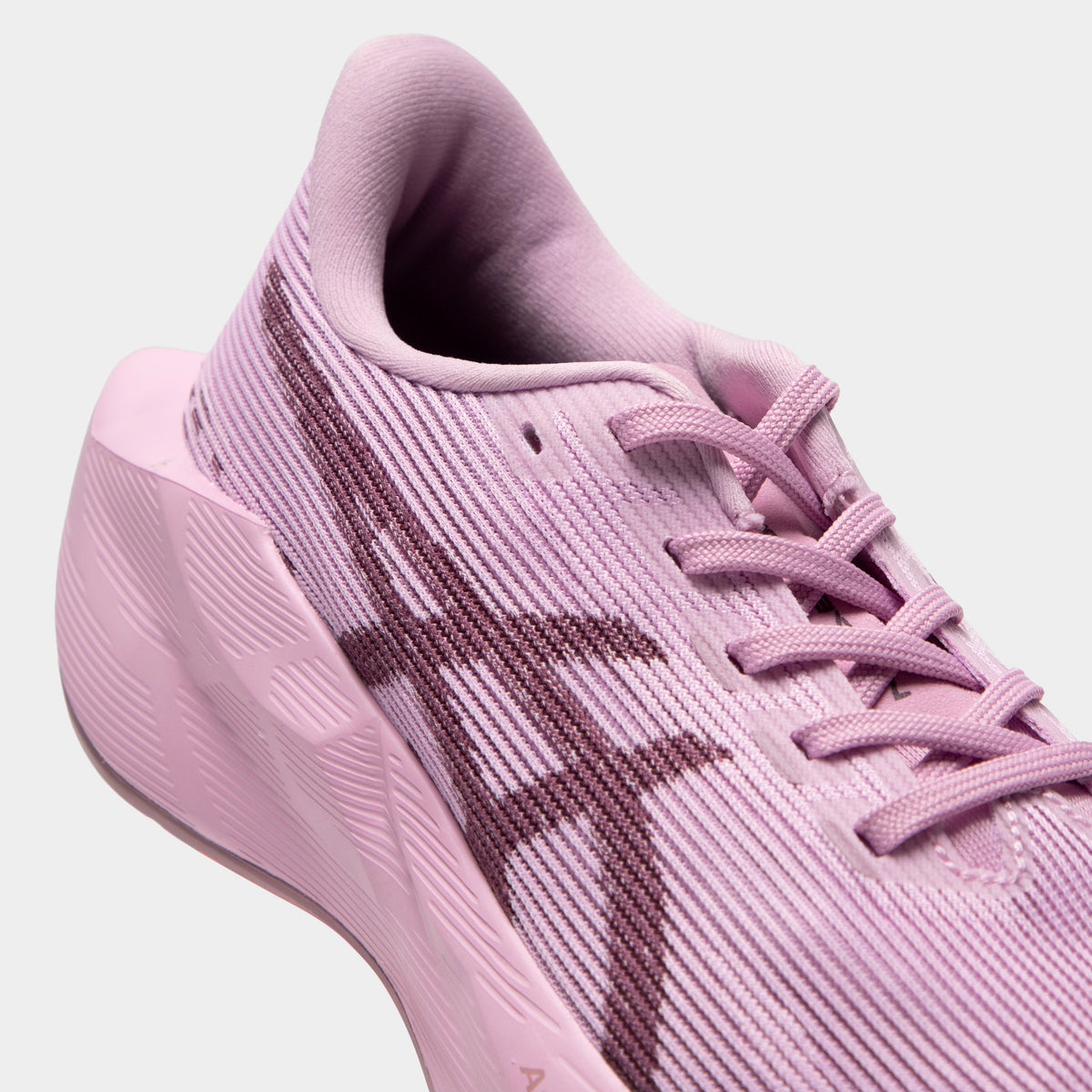 ASICS Juniors' Novablast 5. Close-up of hazy lilac and dark prune junior running shoe showing tonal laces, mesh panels, dark ASICS stripes and padded collar.
