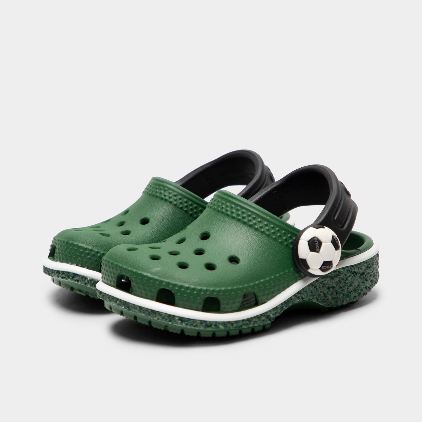 Crocs Infants' Classic Funlab Clog. Three-quarter view of turf green infant clogs with ventilation holes, raised heel straps and soccer-inspired details.