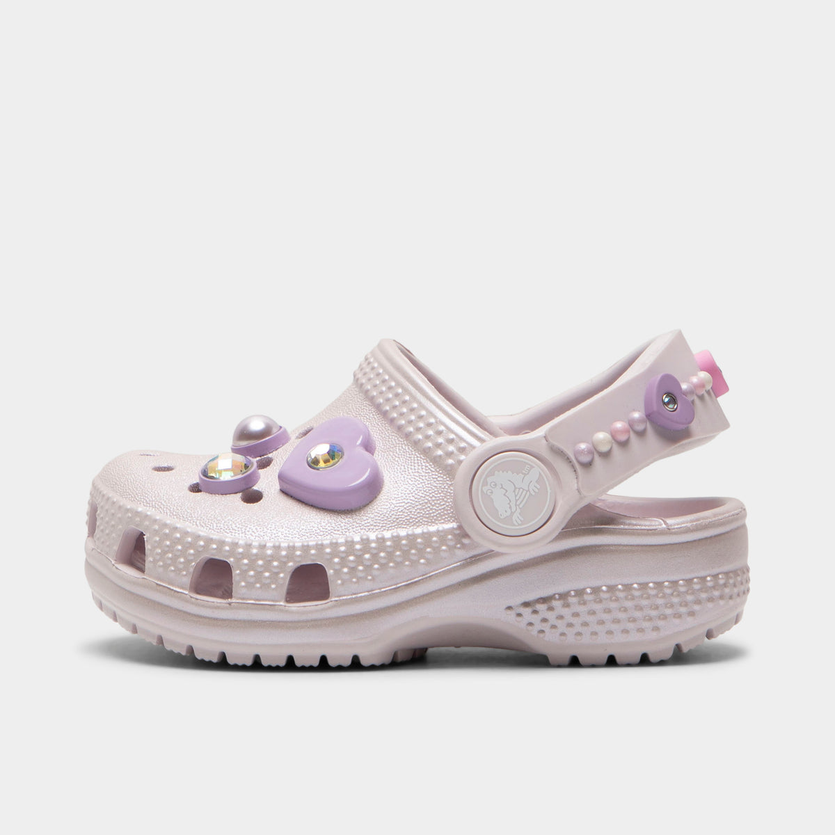 Crocs Infants' Classic Pearls and Heart Shine Clog. Side view of grape ice infant clog with ventilation holes, pivoting heel strap and decorative pearl and heart charms.