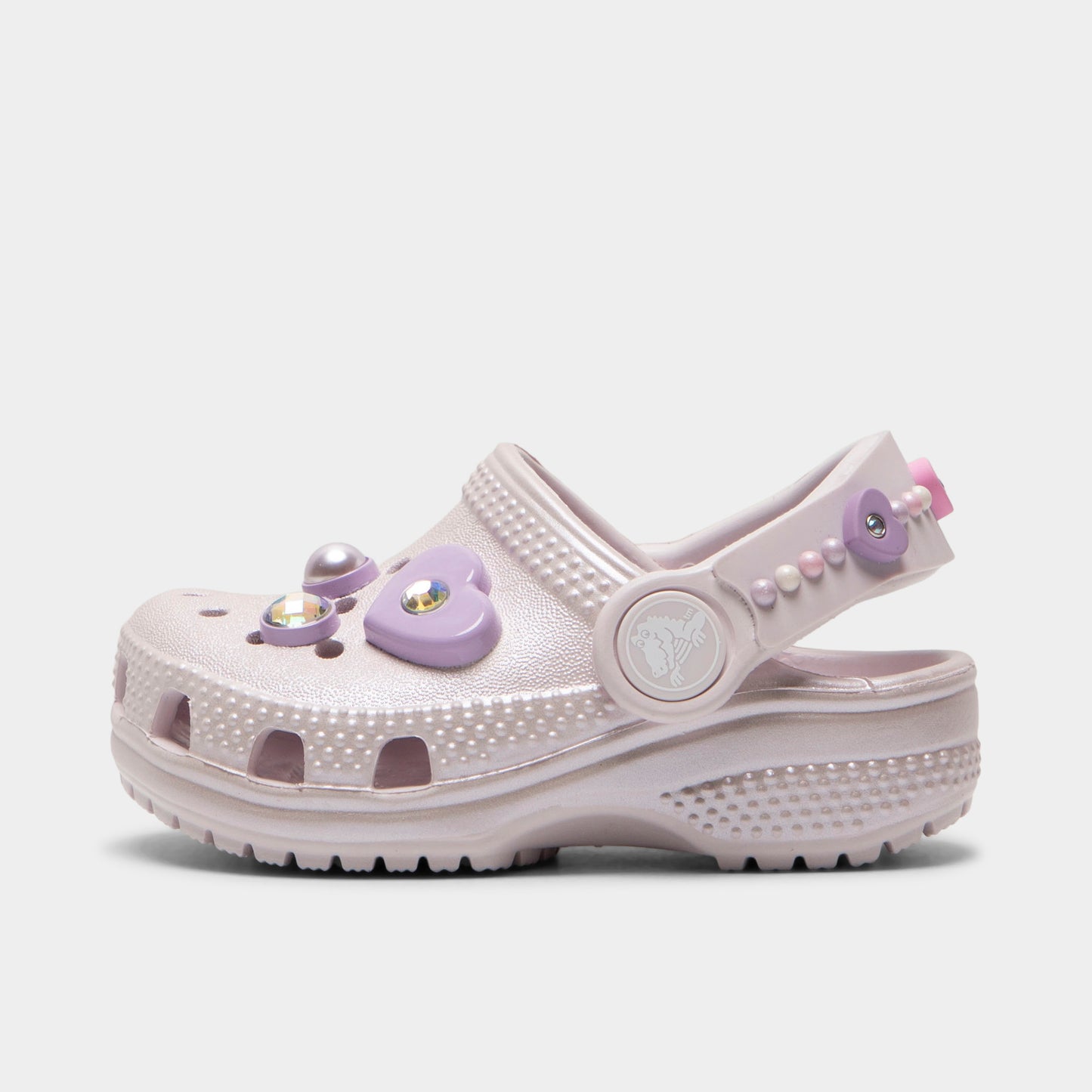 Crocs Infants' Classic Pearls and Heart Shine Clog. Side view of grape ice infant clog with ventilation holes, pivoting heel strap and decorative pearl and heart charms.