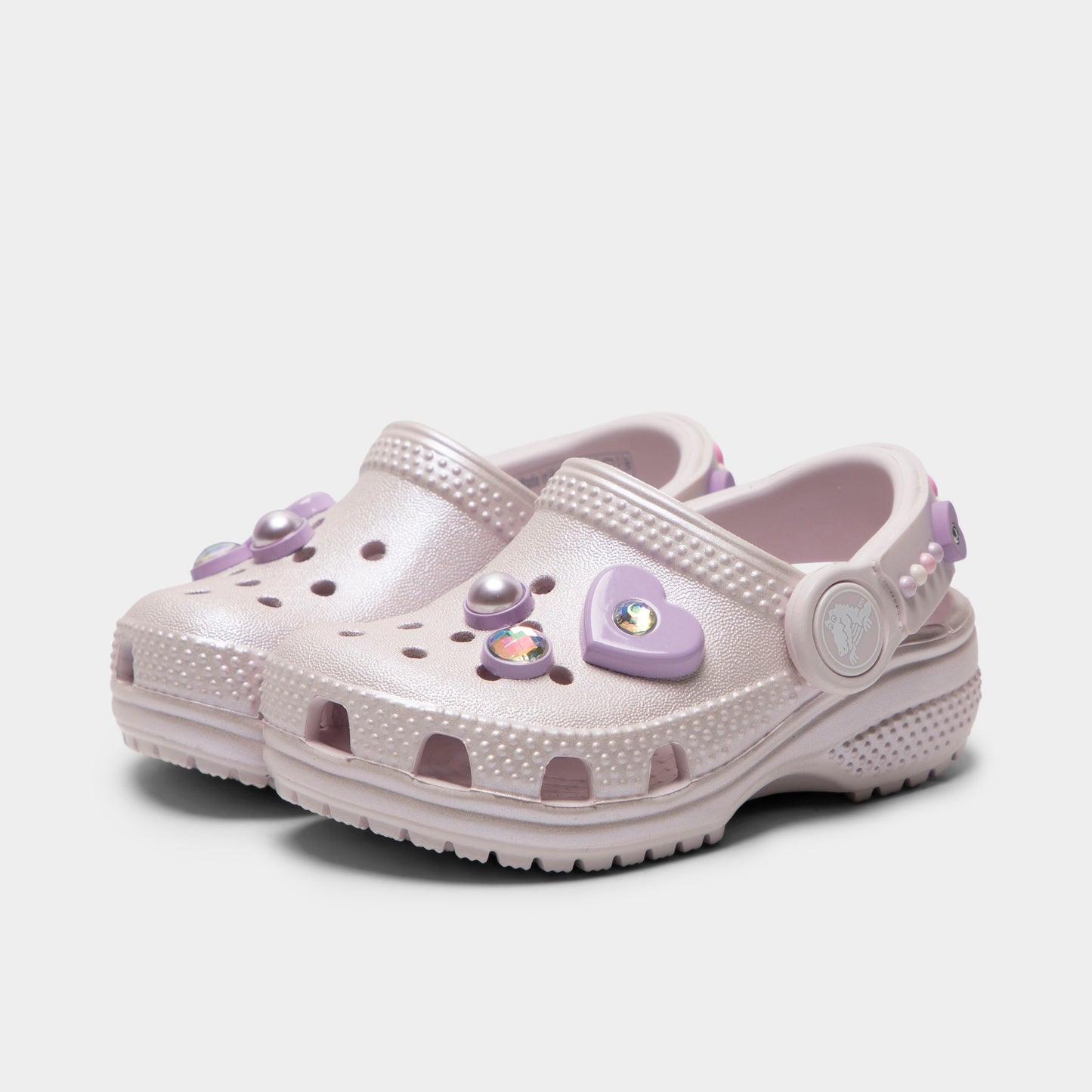 Crocs Infants' Classic Pearls and Heart Shine Clog. Three-quarter view of grape ice infant clogs with ventilation holes, raised heel straps and decorative charms.