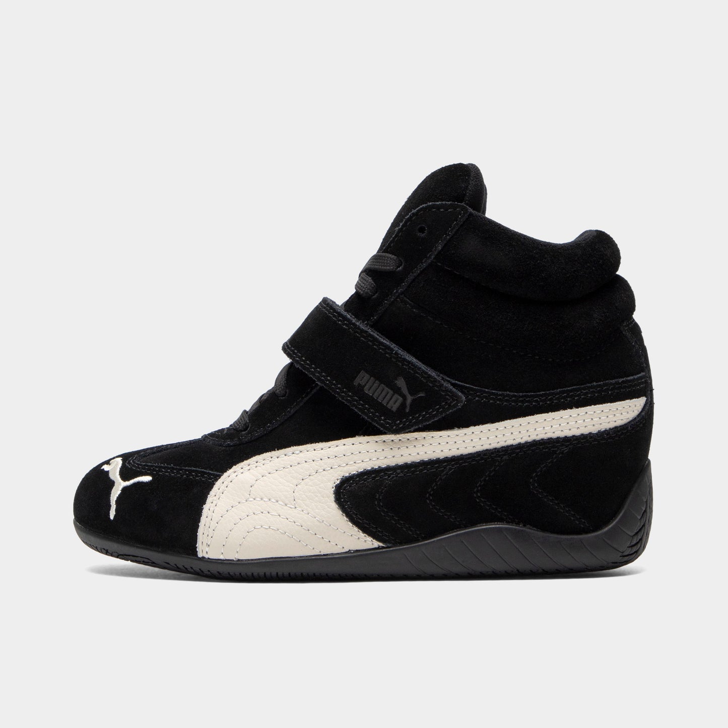 Puma Women's Speedcat Wedge. Side view of black and white wedge sneaker with white Formstrip, hook-and-loop strap and sculpted heel.