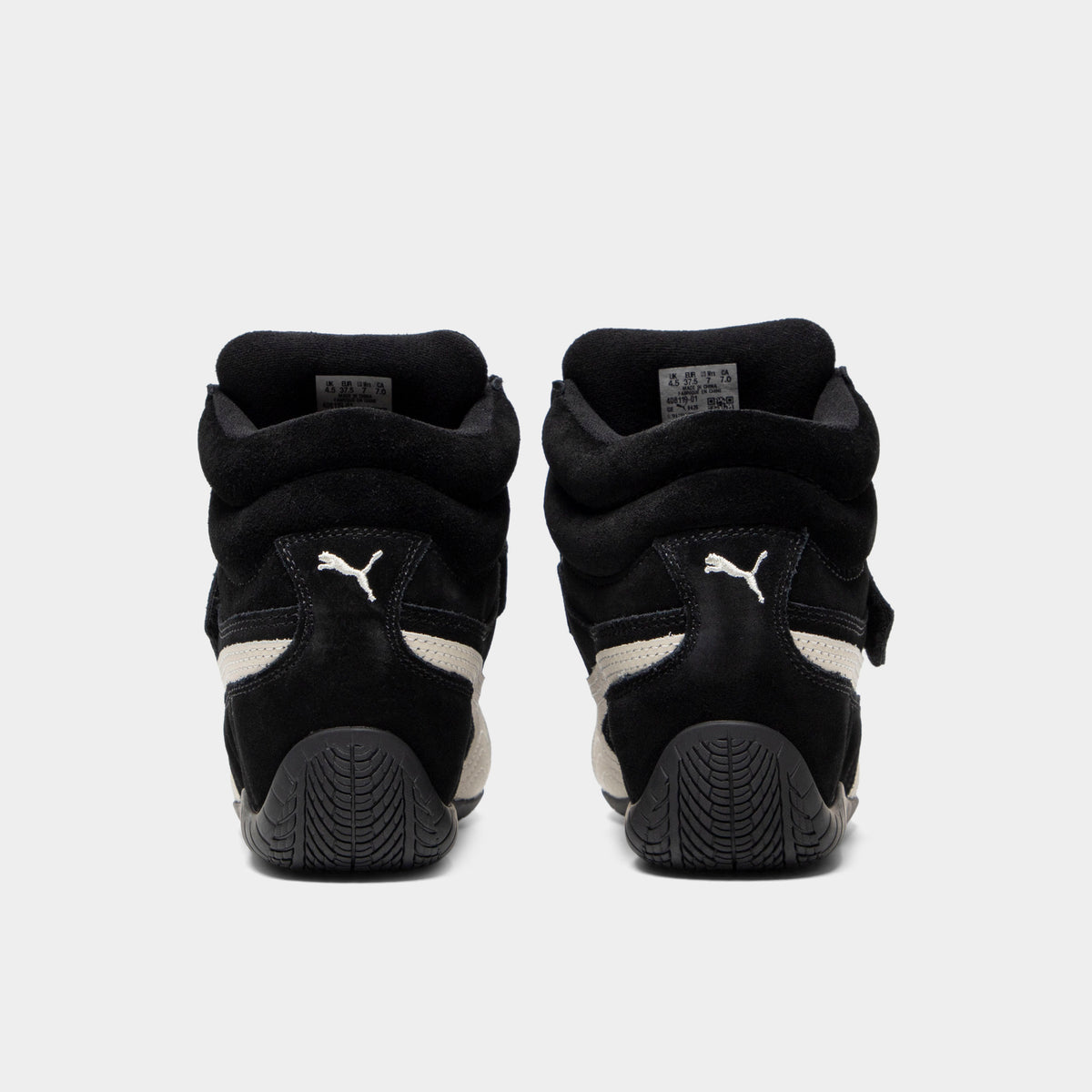 Puma Women's Speedcat Wedge. Rear view of black and white wedge sneakers with padded heel panels, pull tabs and black soles.