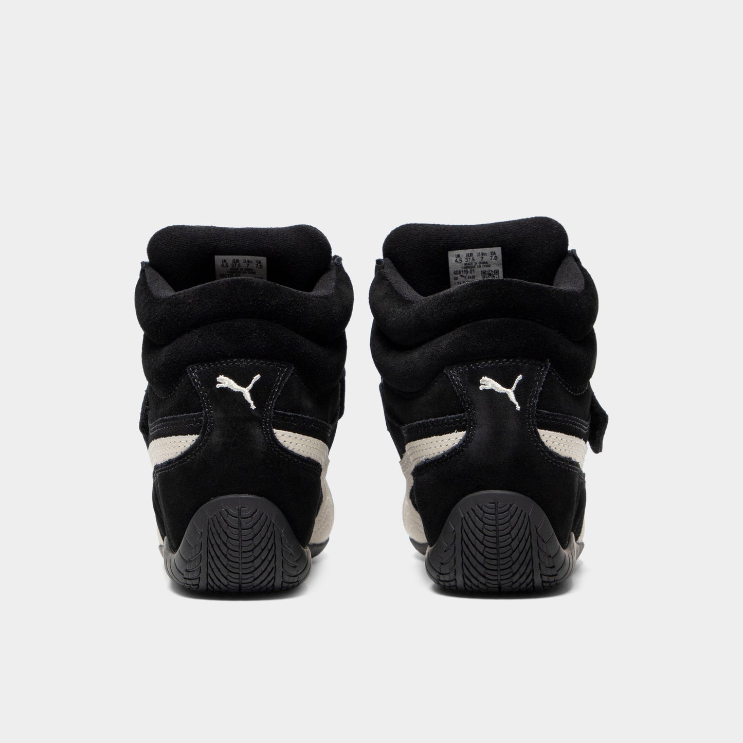 Puma Women's Speedcat Wedge. Rear view of black and white wedge sneakers with padded heel panels, pull tabs and black soles.
