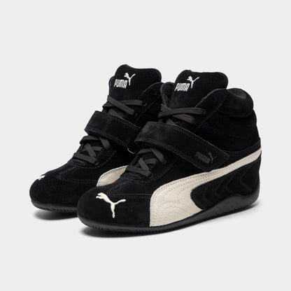 Puma Women's Speedcat Wedge. Three-quarter view of black and white wedge sneakers with padded collars, hook-and-loop straps and white Formstrips.