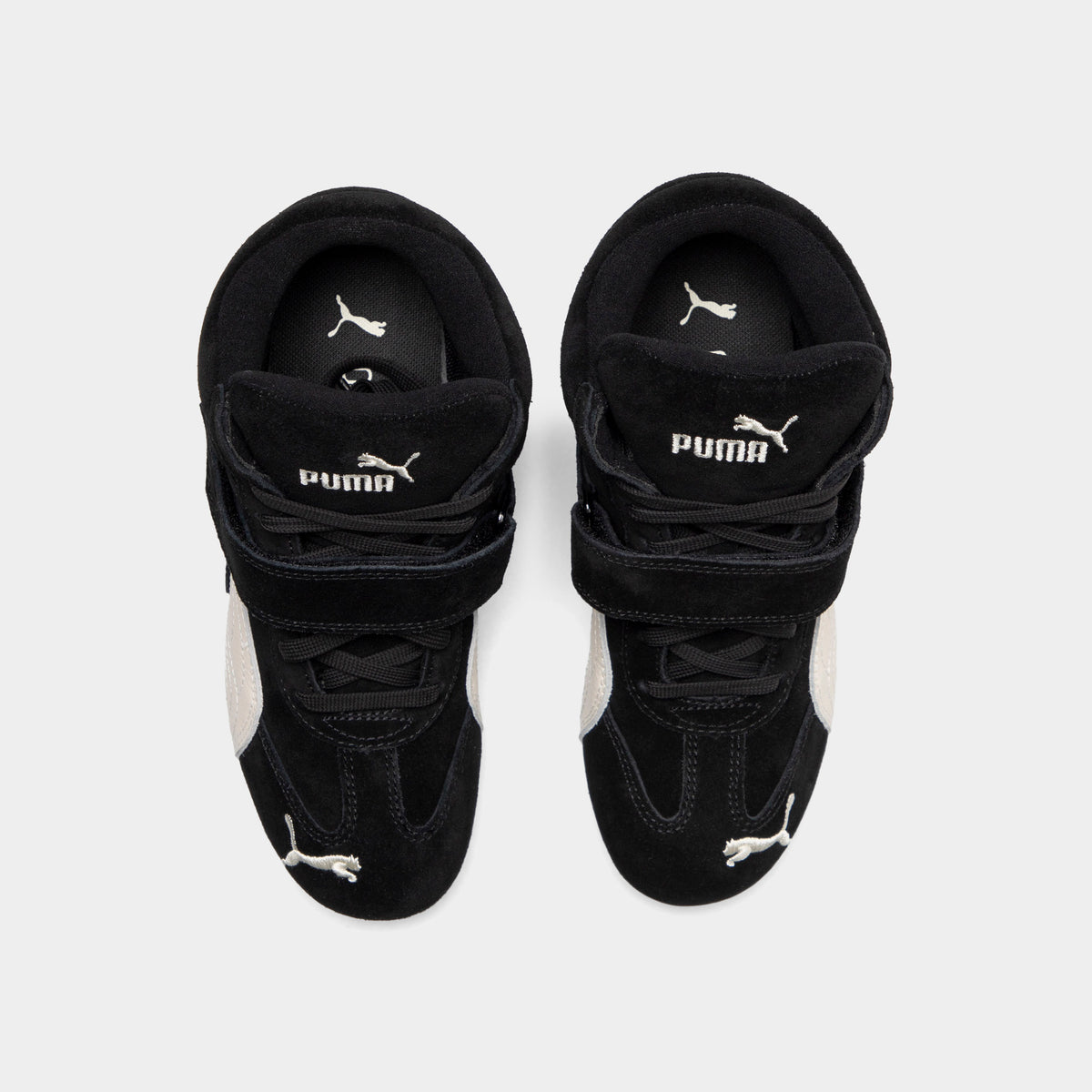 Puma Women's Speedcat Wedge. Top view of black and white wedge sneakers showing padded tongues, hook-and-loop straps and black insoles.